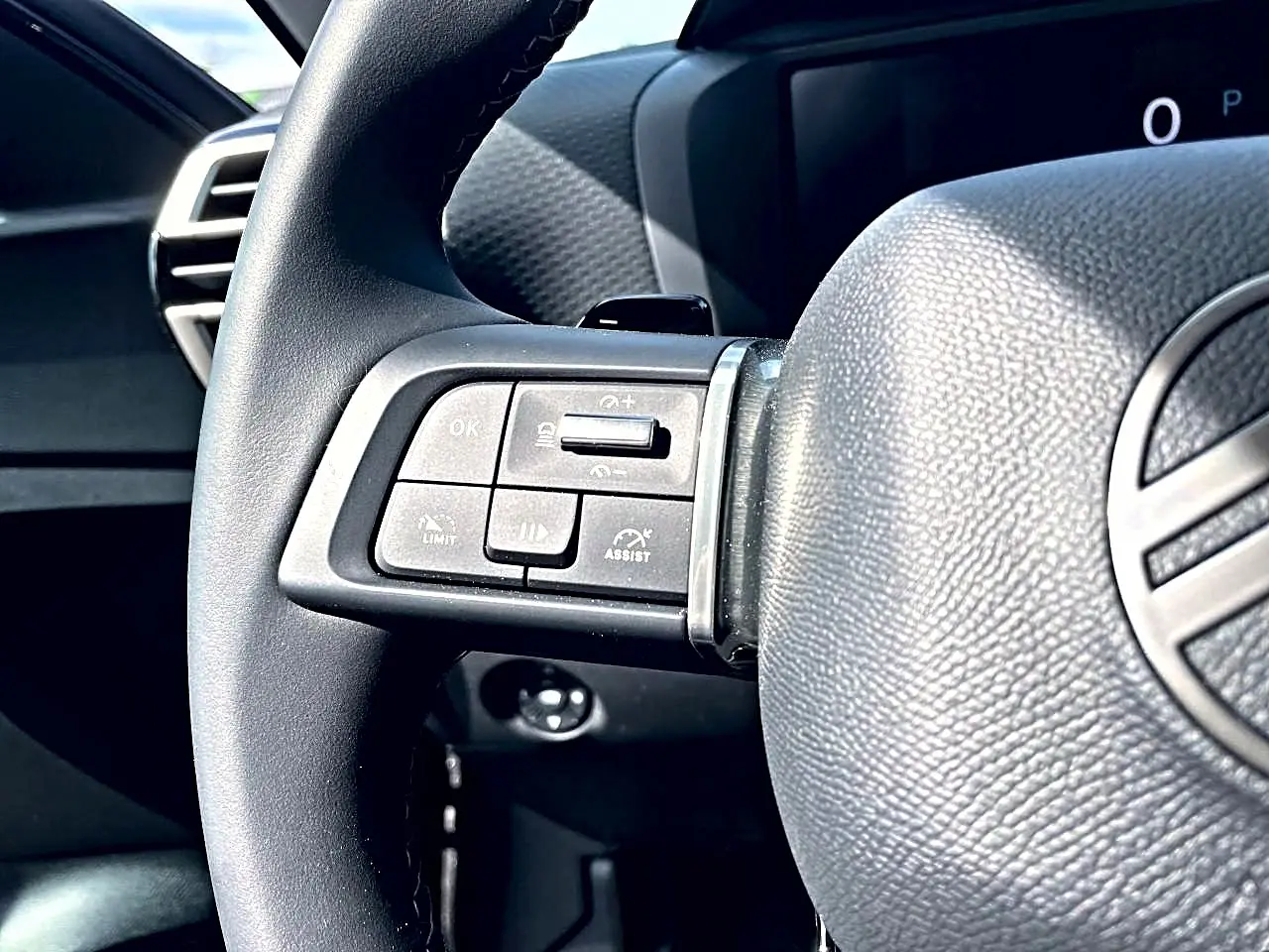 Gros plan sur le côté gauche du volant cuir noir d'une Citroën C4 X 2025, avec commandes intégrées visibles.