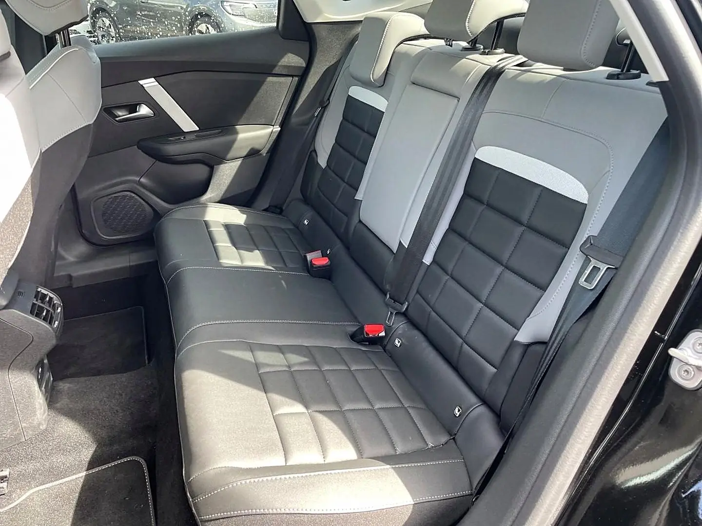 Vue côté droit de la banquette arrière bi-ton noir et gris clair du Citroën C4 X 1.2 hybride 2025, avec ceinture de sécurité visible.