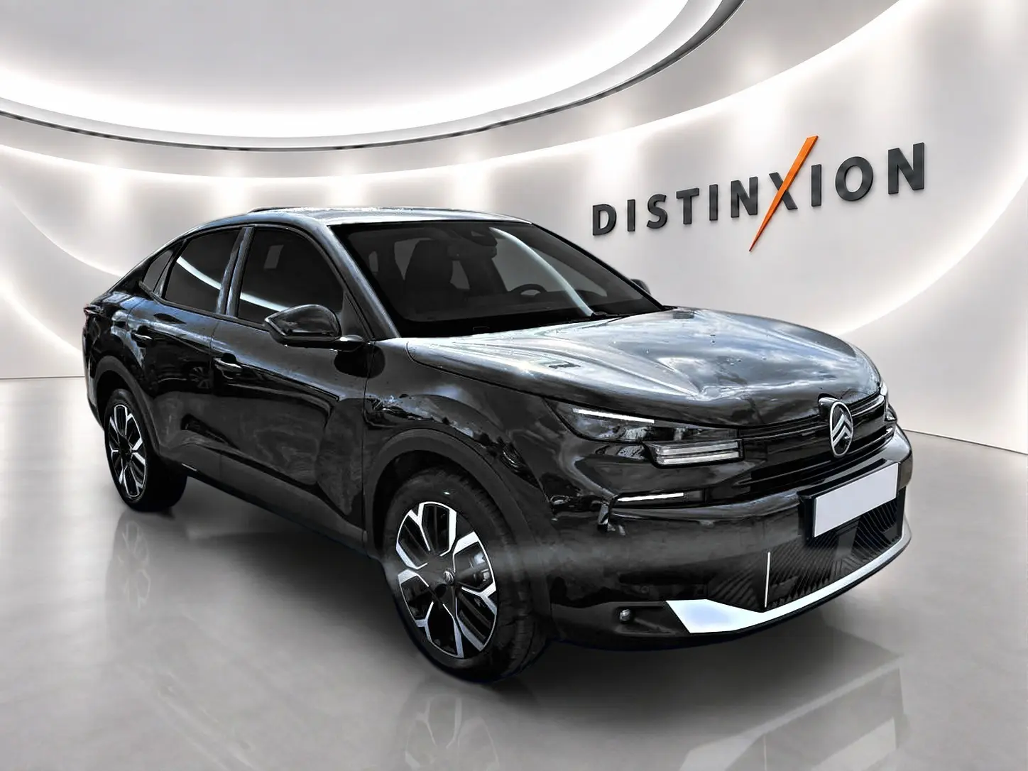 Citroën C4 X noire vue 3/4 avant droit en intérieur, avec jantes alu et signature lumineuse LED distinctive.