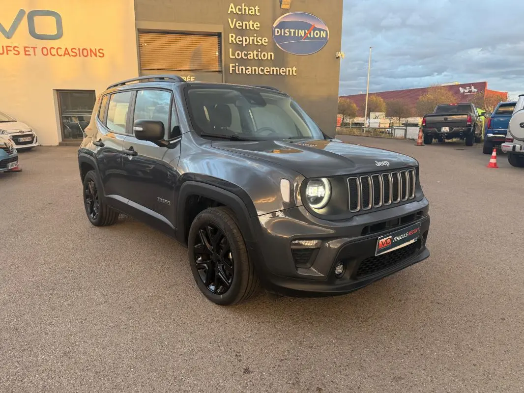 Jeep Renegade gris anthracite en 3/4 avant droit, avec jantes alliage noires et barres de toit visibles.