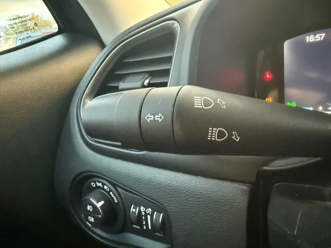 Gros plan sur la commande des phares et clignotants à gauche du volant dans l'habitacle d'un Jeep Renegade gris anthracite 2024.