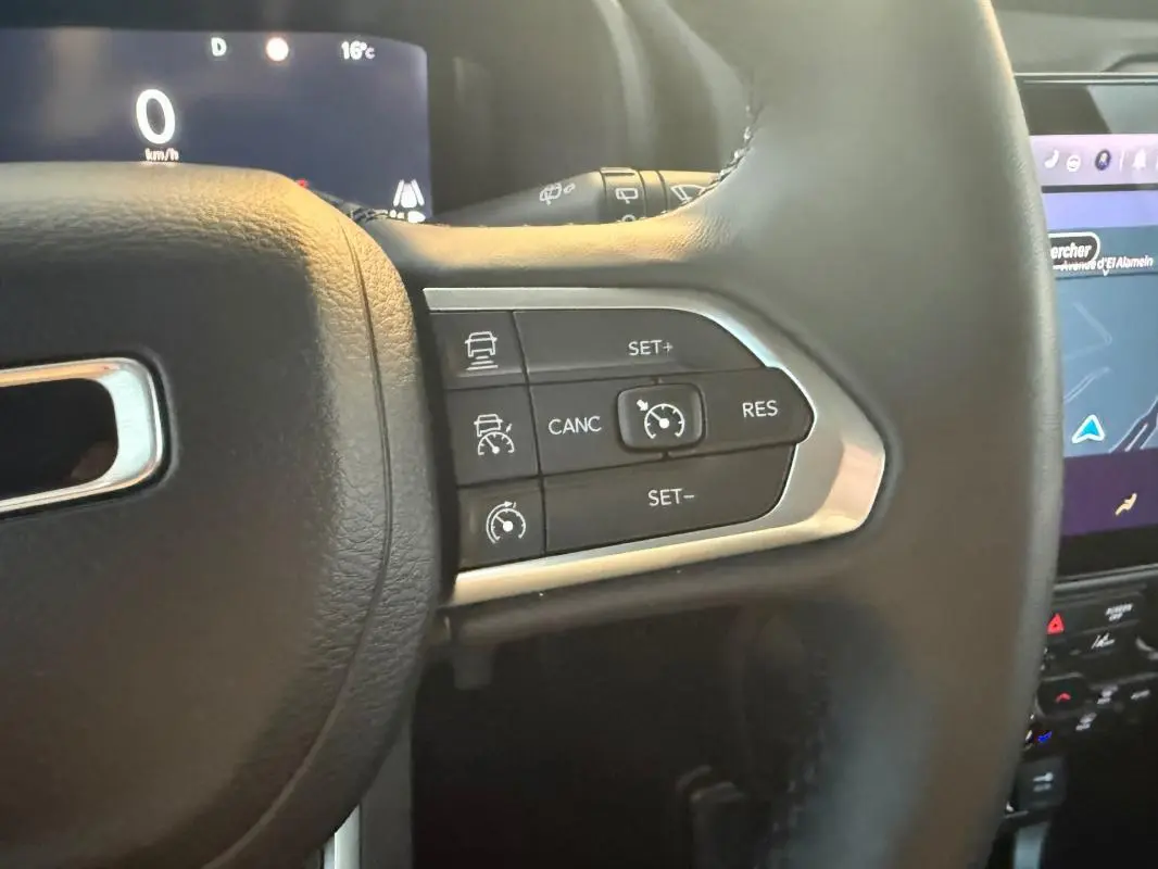 Gros plan sur les commandes du régulateur de vitesse au volant cuir noir du Jeep Renegade 2024 e-Hybrid Summit.