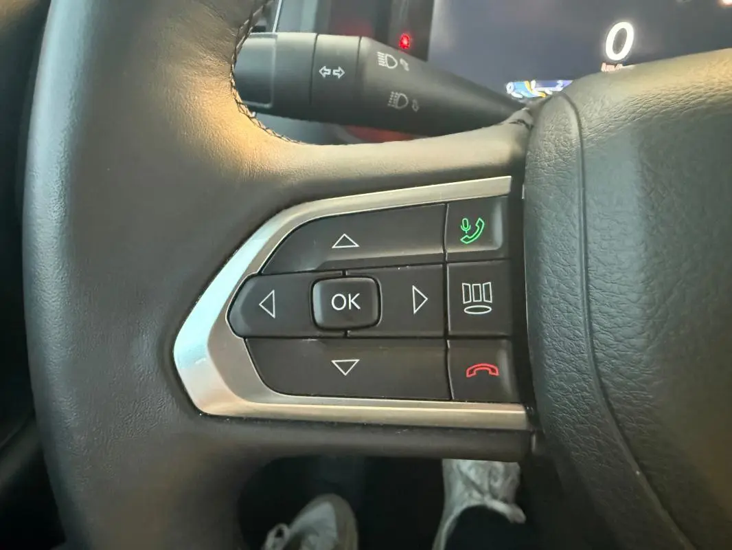 Gros plan sur les commandes du volant à gauche du Jeep Renegade gris anthracite 2024, avec boutons de navigation et appel.
