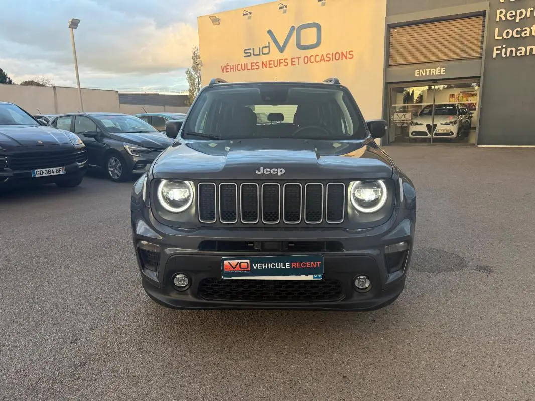 Vue frontale d'un Jeep Renegade gris anthracite 2024 avec phares allumés et calandre distinctive à sept fentes.