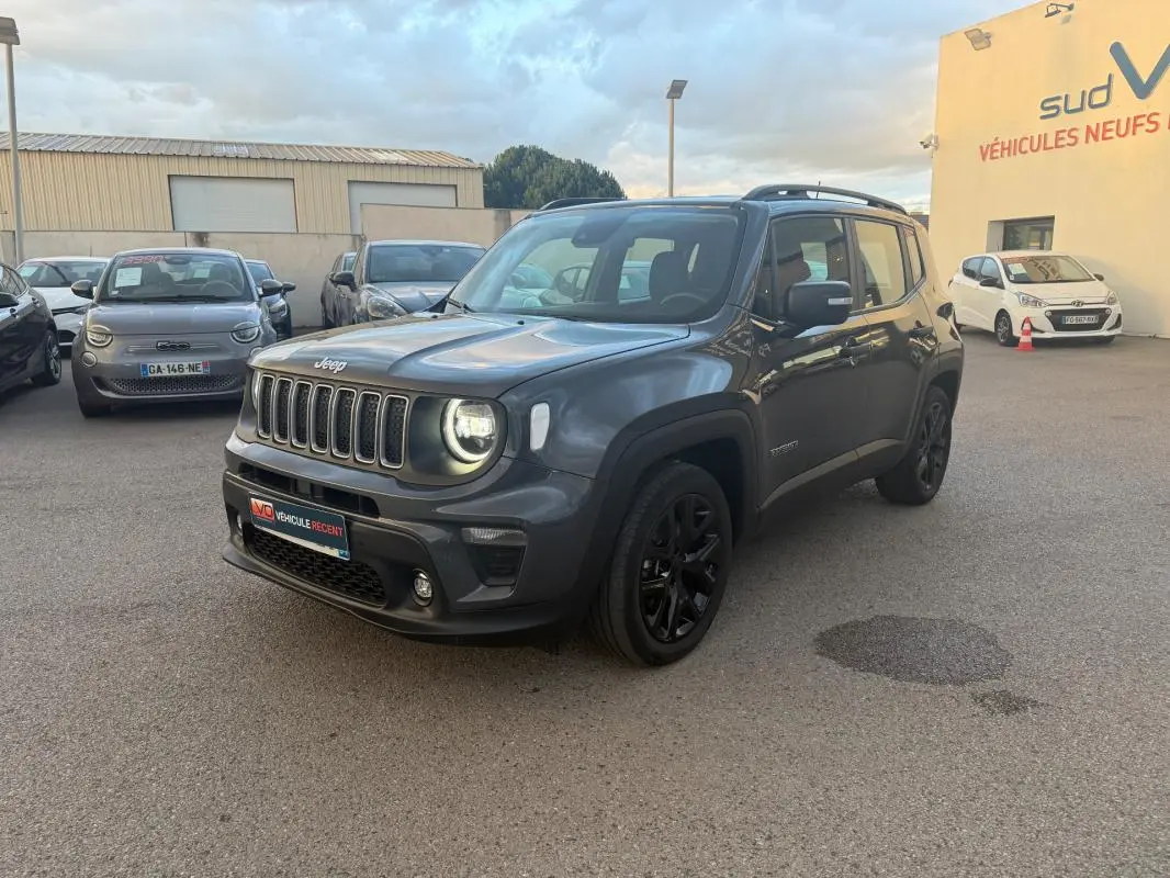 Jeep Renegade gris anthracite en 3/4 avant droit, avec jantes alliage noires et barres de toit visibles.