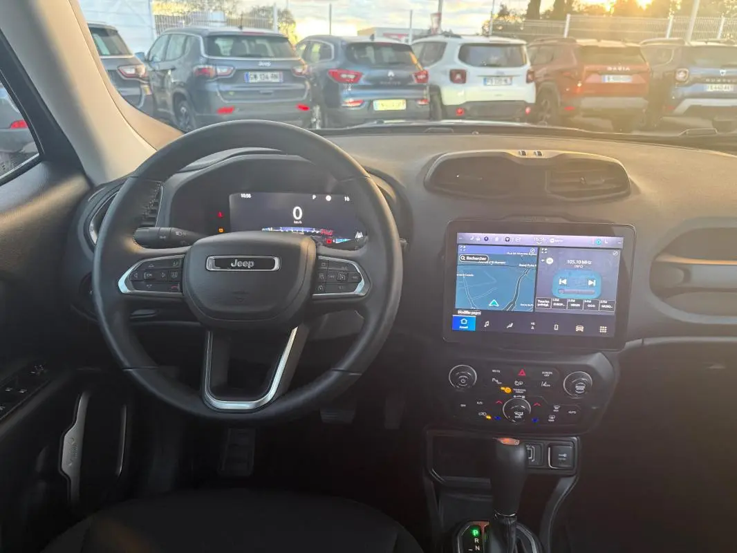 Vue intérieure du tableau de bord du Jeep Renegade 2024 gris anthracite, avec volant multifonction et écran tactile GPS allumé.