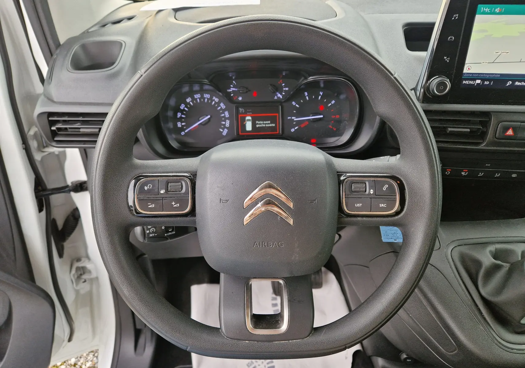 Vue intérieure centrée sur le volant noir du Citroën Berlingo blanc 2021 avec tableau de bord et écran tactile visible.