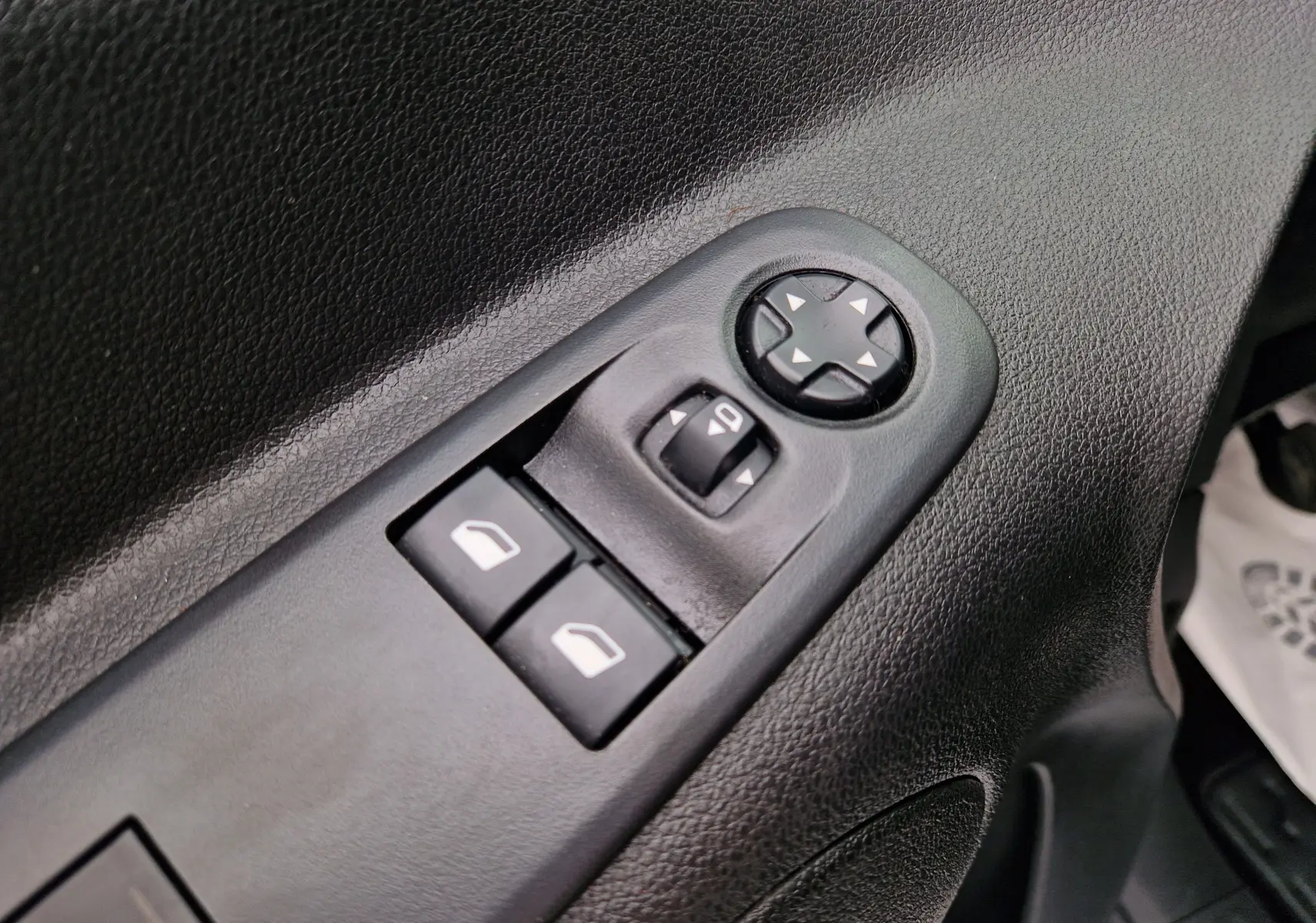 Gros plan sur les commandes de réglage des rétroviseurs et des vitres électriques côté conducteur du Citroën Berlingo blanc de 2021.