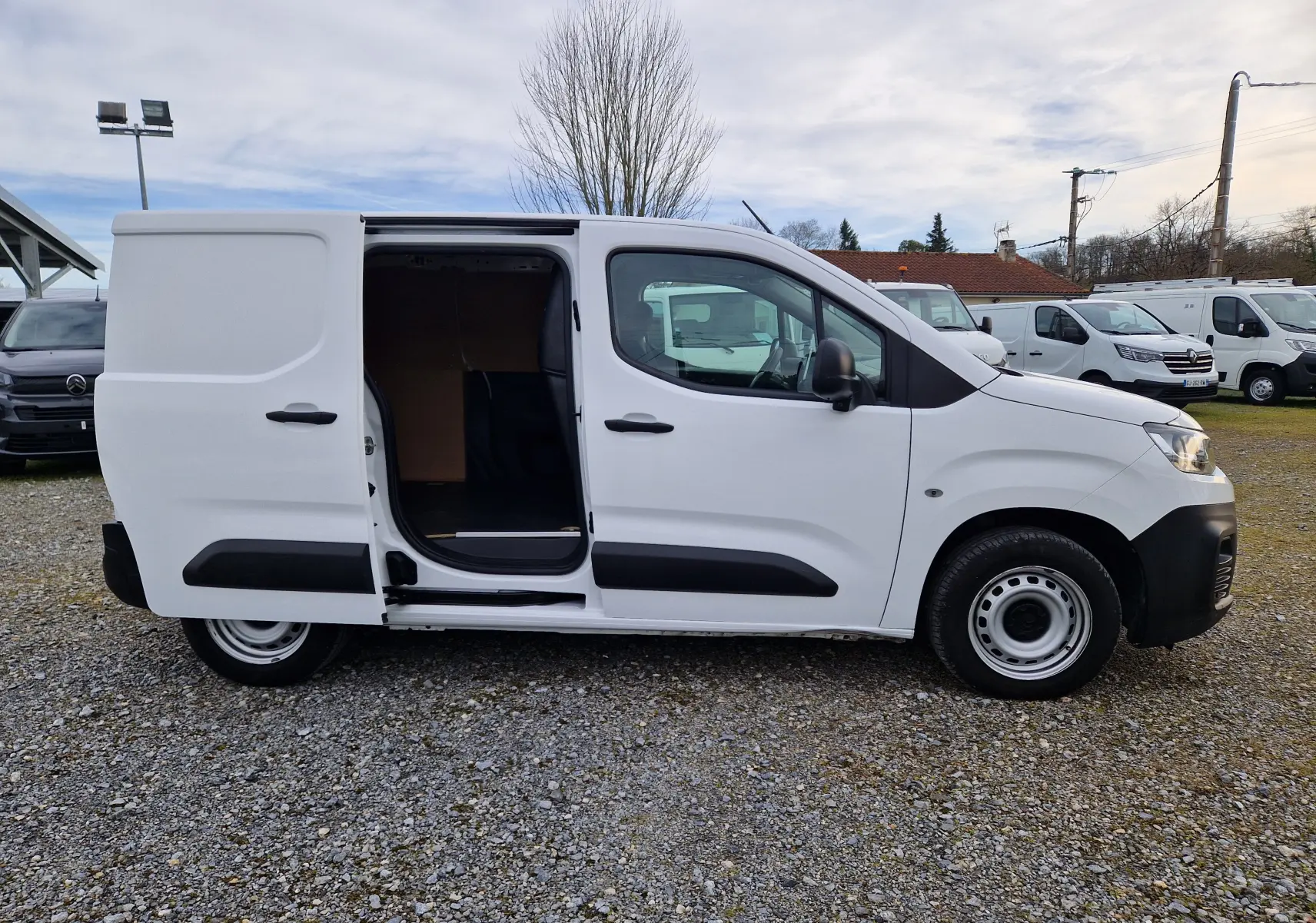 Vue de profil côté gauche d’un Citroën Berlingo blanc 2021 avec porte latérale coulissante ouverte montrant l’intérieur vide.