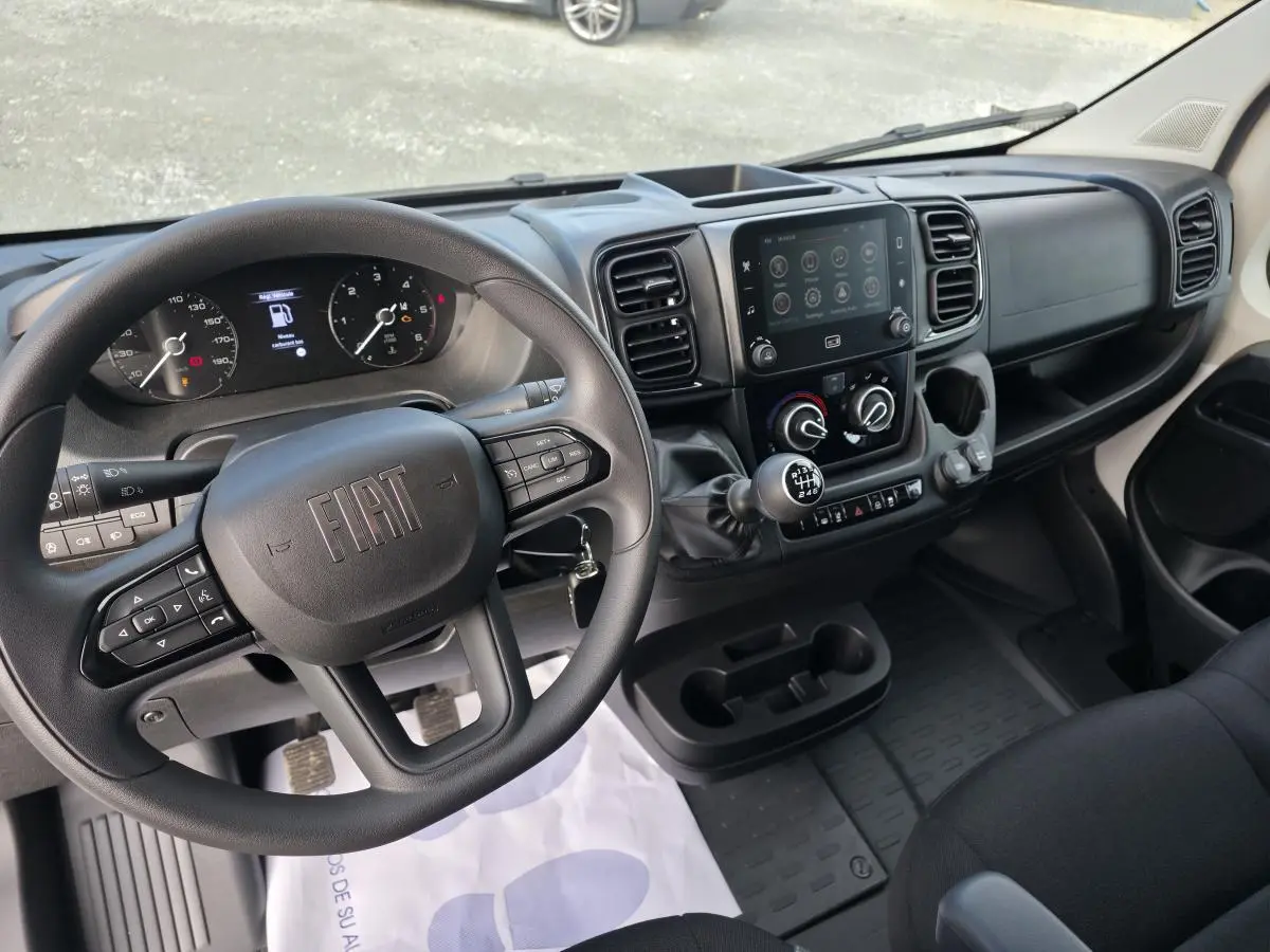 Vue intérieure du poste de conduite du Fiat Ducato Fourgon blanc, avec volant multifonction et écran tactile central 7 pouces.