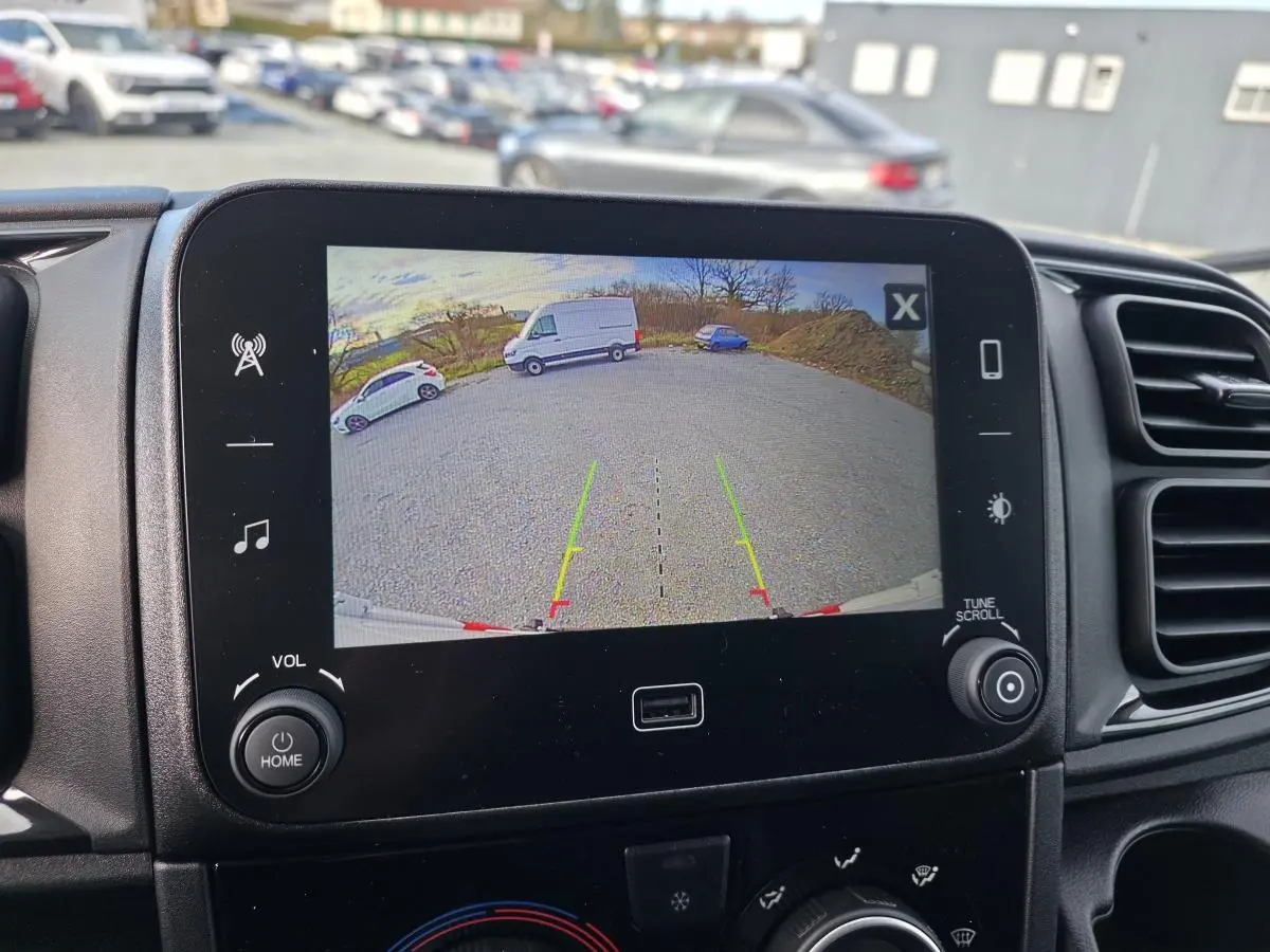 Écran central montrant la caméra de recul du Fiat Ducato Fourgon blanc, vue arrière sur parking extérieur.