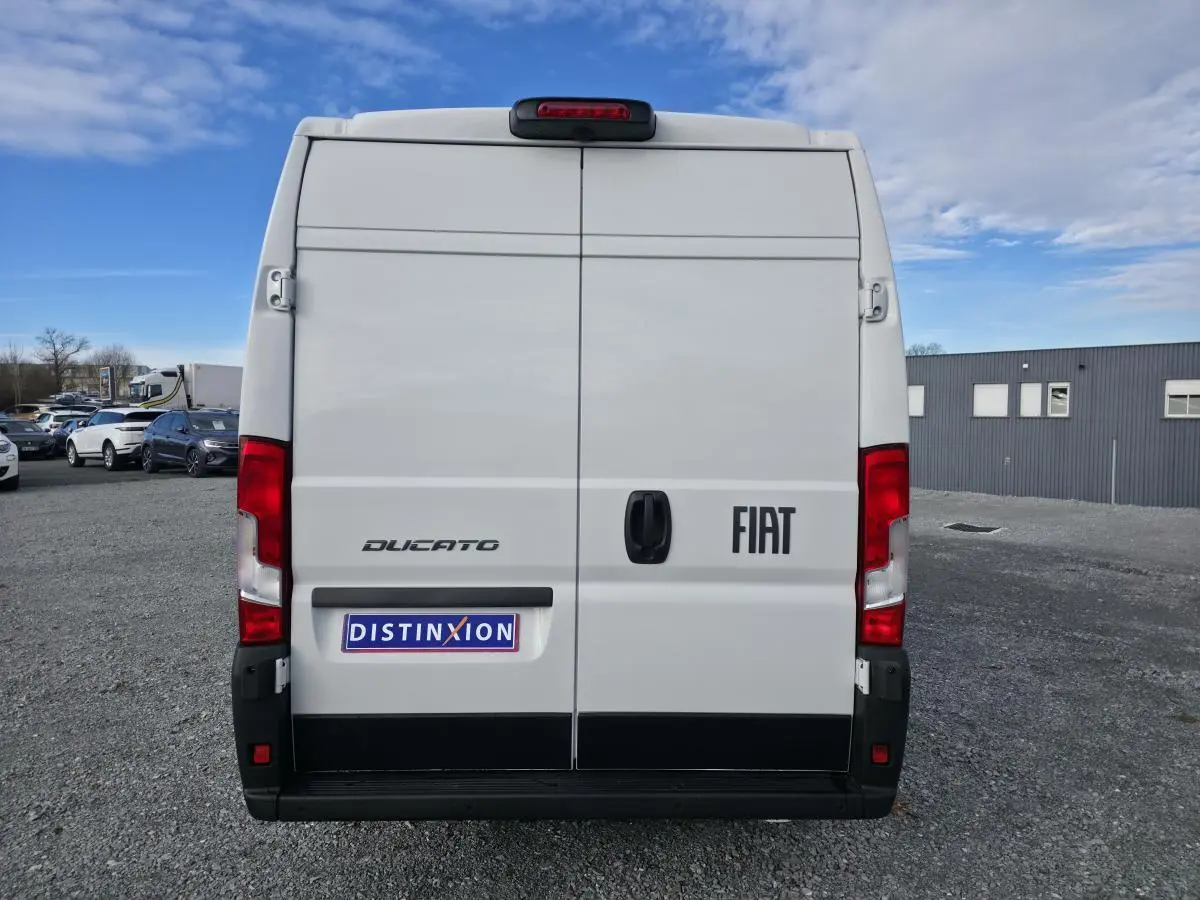Vue arrière d’un FIAT Ducato Fourgon blanc 2025 avec portes battantes et feux arrière rouges visibles.