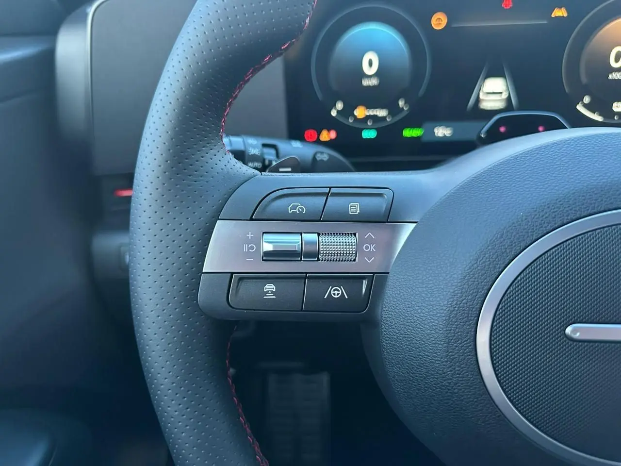Gros plan sur le volant cuir perforé avec commandes multifonctions et tableau de bord numérique du Hyundai Kona 2026 gris Ecotronic.