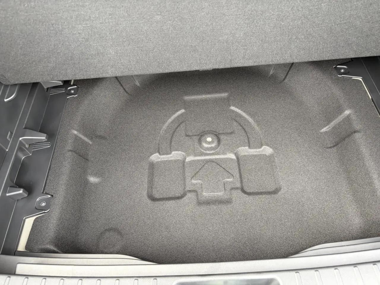 Coffre ouvert du Hyundai Kona 2026 gris Ecotronic, vue plongeante sur le rangement sous plancher sans roue de secours.