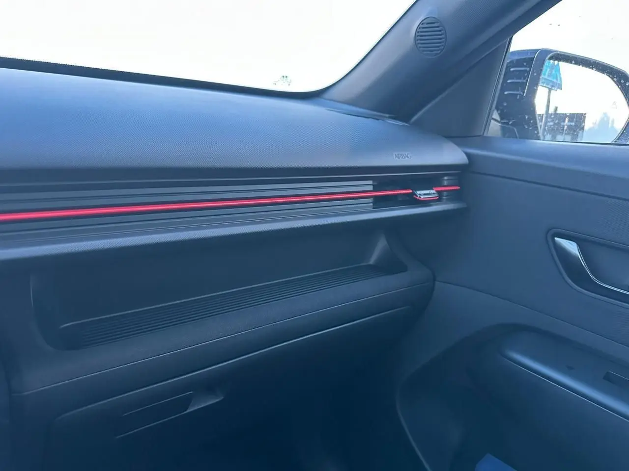Vue intérieure côté passager du tableau de bord noir avec bande LED rouge du Hyundai Kona 2026 finition N Line.