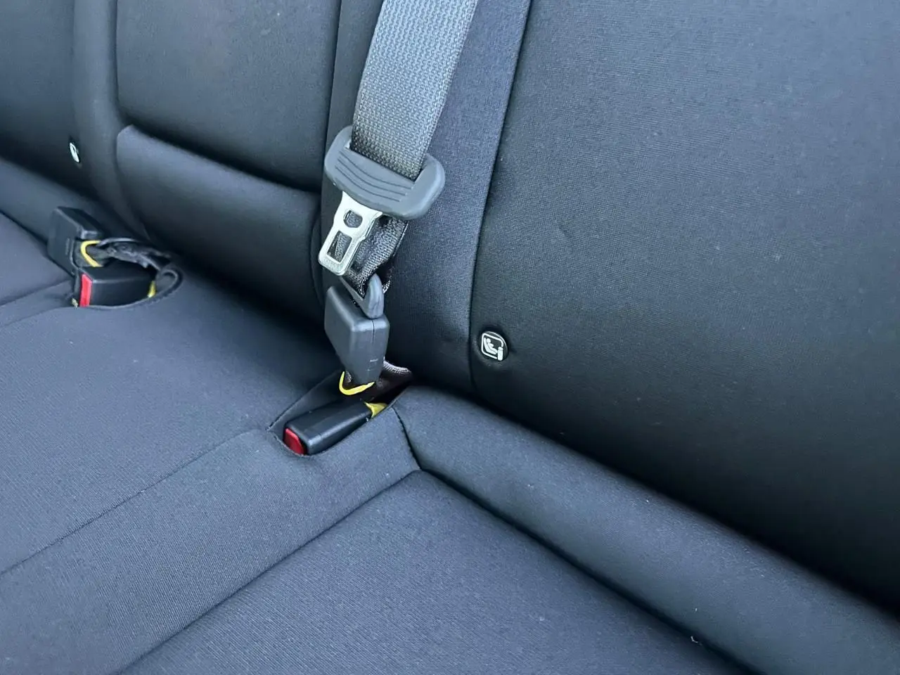 Gros plan sur la banquette arrière noire du Hyundai Kona II 1.6 Hybrid N Line avec ceinture et fixation Isofix visible.