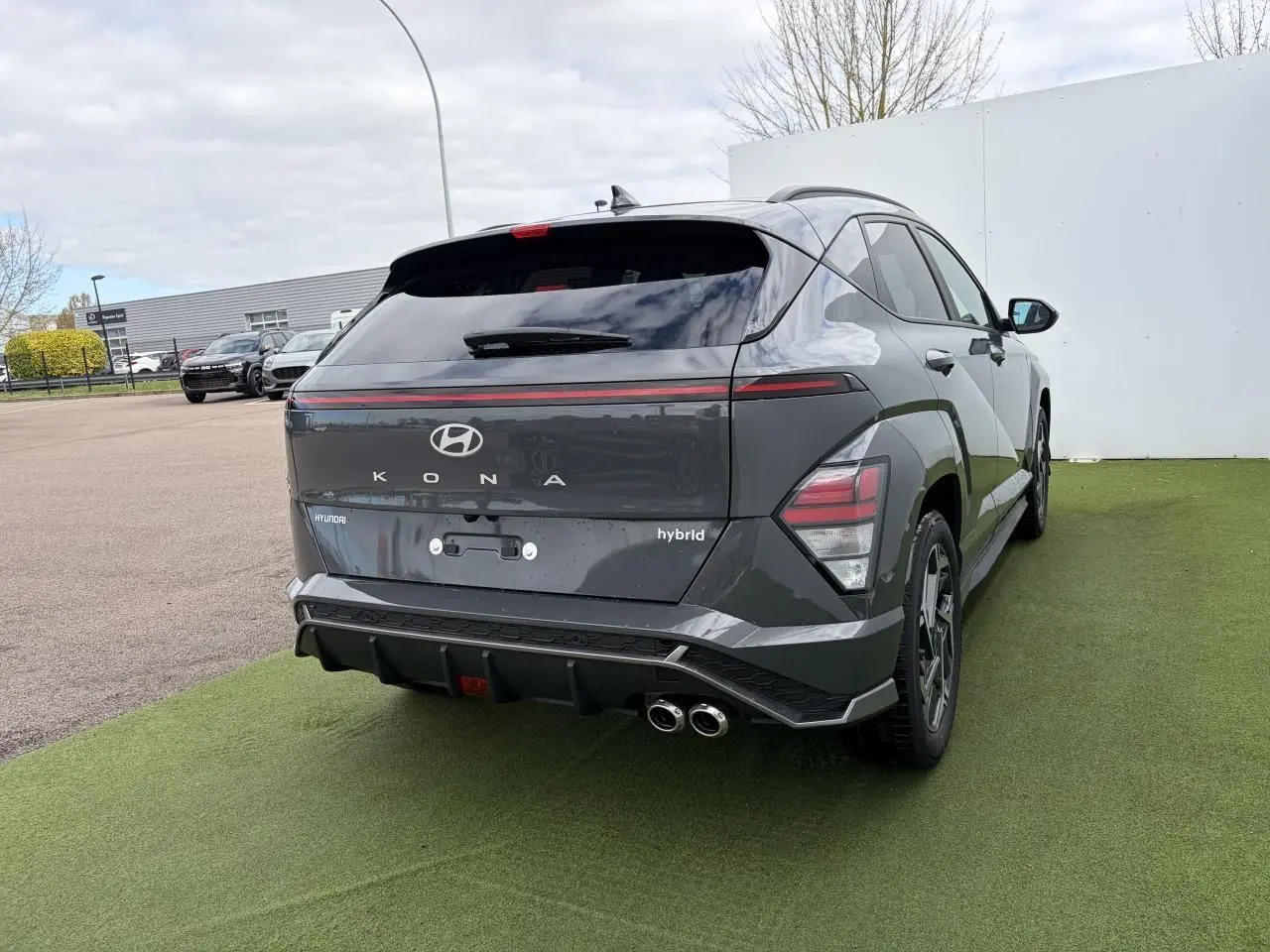 Vue 3/4 arrière droite du Hyundai KONA II hybride gris Ecotronic avec double sortie d'échappement et feux arrière LED.