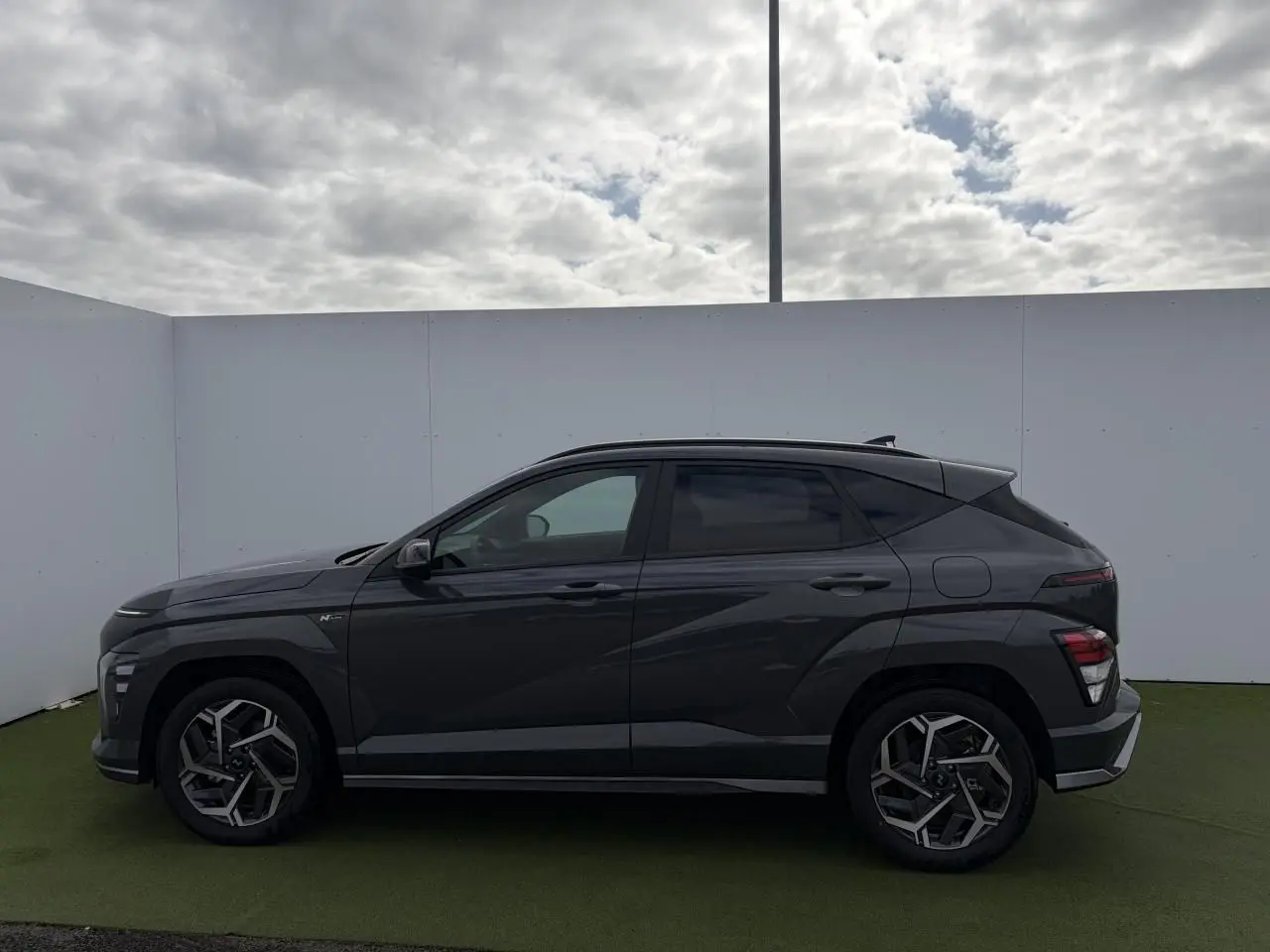 Vue latérale droite d'un Hyundai Kona II 1.6 Hybrid N Line 2026 en gris métallisé Ecotronic avec jantes alliage 18 pouces.