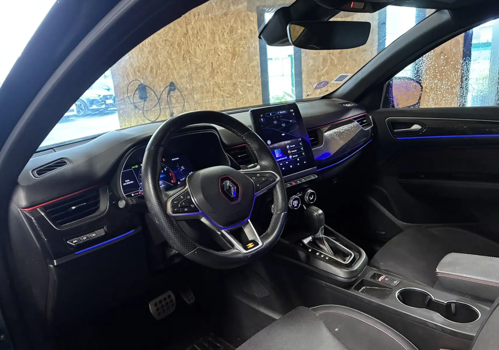 Vue intérieure côté conducteur du Renault Arkana 1.3 TCE 140 RS-LINE 2021, tableau de bord noir avec éclairage bleu et écran tactile vertical.