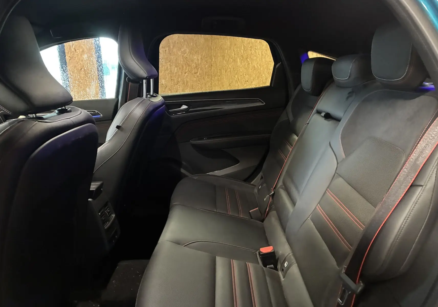 Vue intérieure arrière côté droit du Renault Arkana 1.3 TCE 140 RS-LINE 2021 avec sièges cuir noir et surpiqûres rouges.