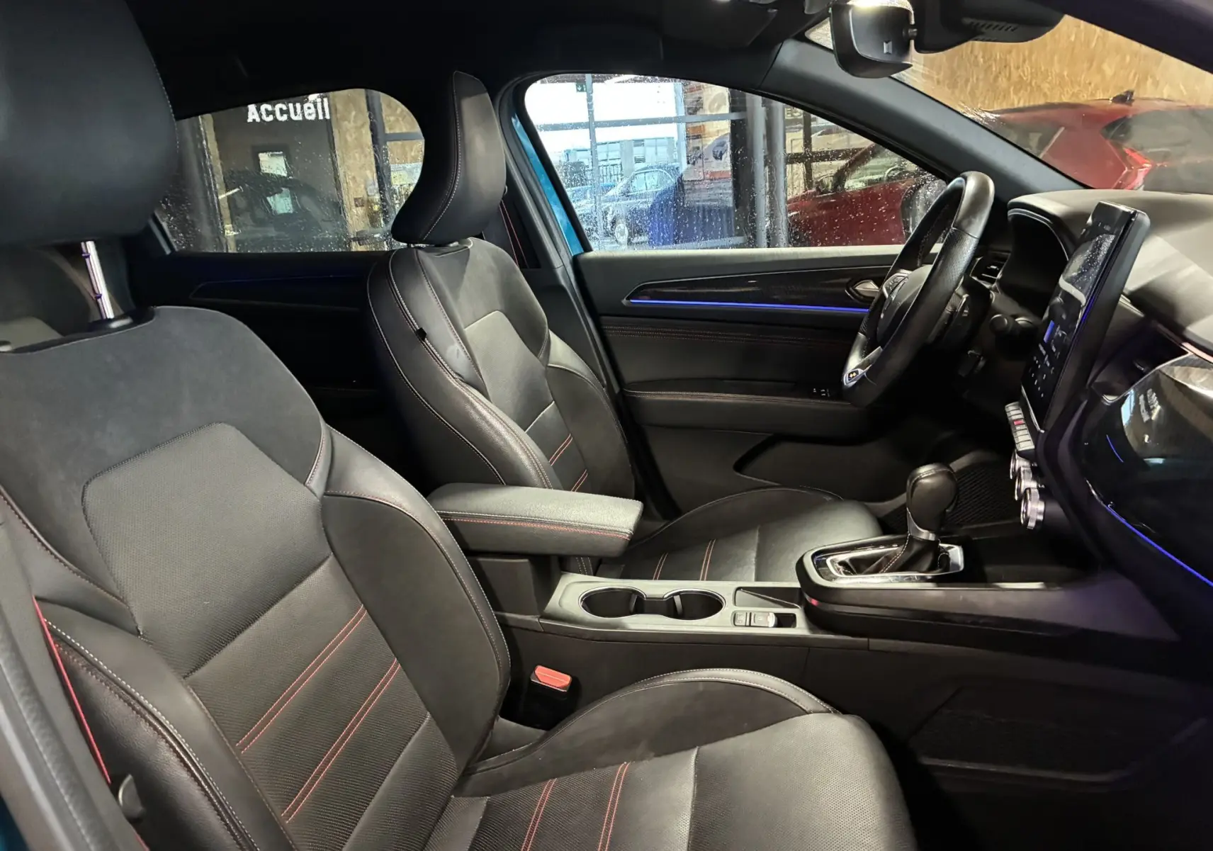 Vue intérieure côté droit du Renault Arkana 1.3 TCE 140 RS-LINE 2021, sièges cuir noir avec surpiqûres rouges et console centrale.