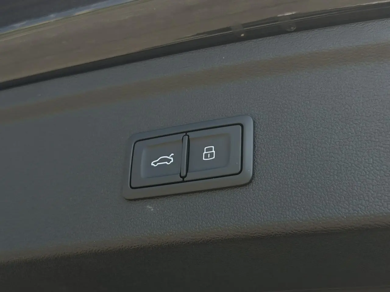 Gros plan sur les boutons d'ouverture et de verrouillage du hayon électrique d'une Audi A3 Sportback noir Mythe.