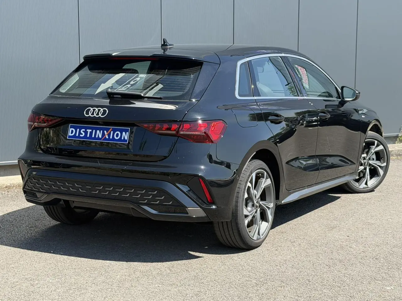 Audi A3 Sportback noir Mythe vue 3/4 arrière droit, avec jantes alliage 5 branches en Y et feux LED distinctifs.
