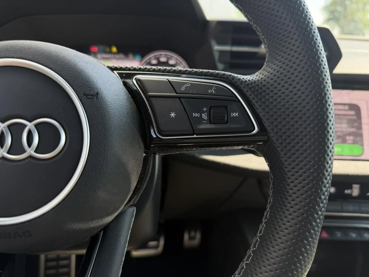 Gros plan sur la partie droite du volant cuir perforé noir de l'Audi A3 Sportback 2025 avec commandes intégrées.
