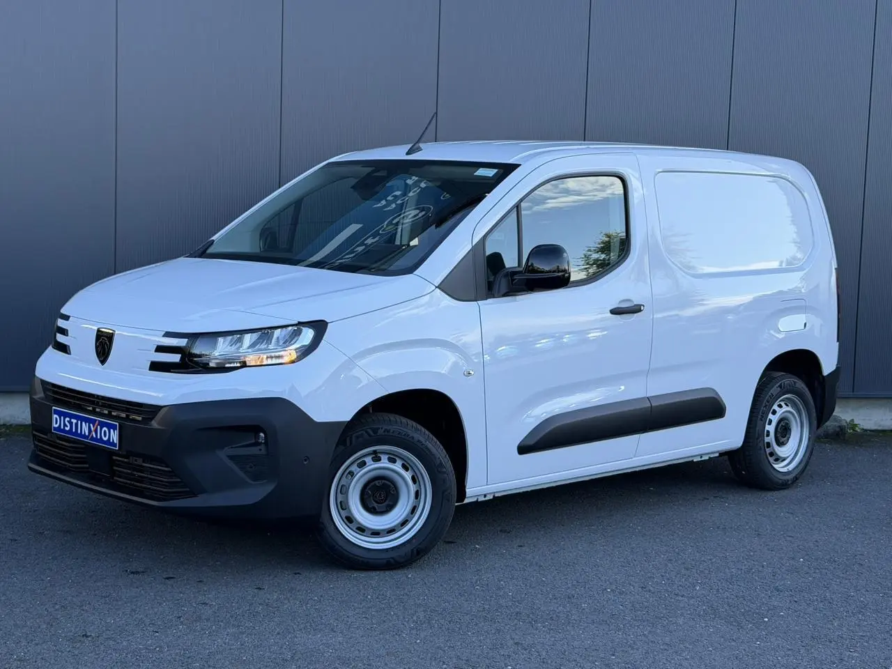 Vue 3/4 avant droit d’un Peugeot Partner blanc Icy avec coques de rétroviseurs noires et protections latérales noires.