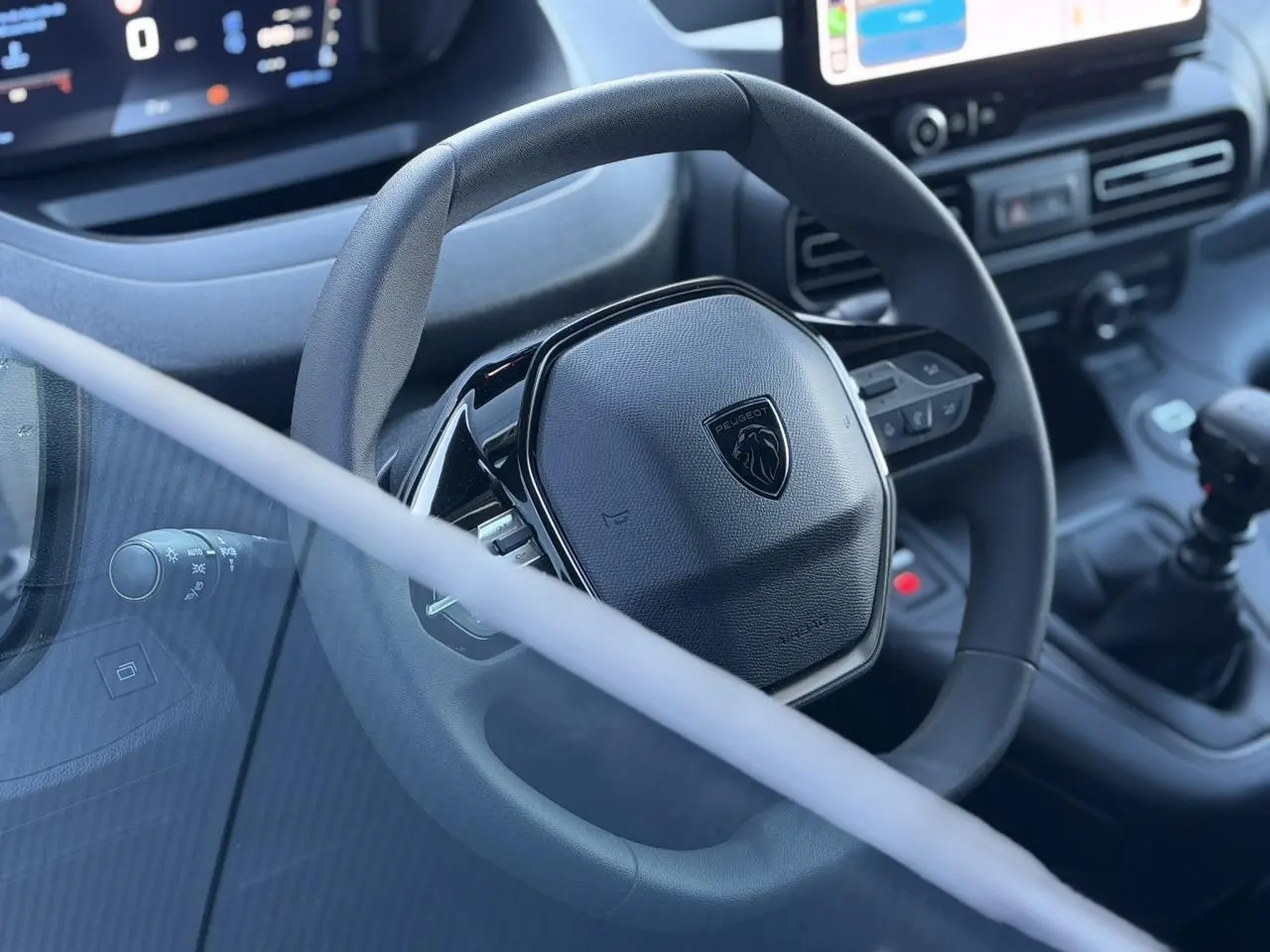 Vue rapprochée du volant noir Peugeot Partner 2026 avec tableau de bord et levier de vitesses manuelle.