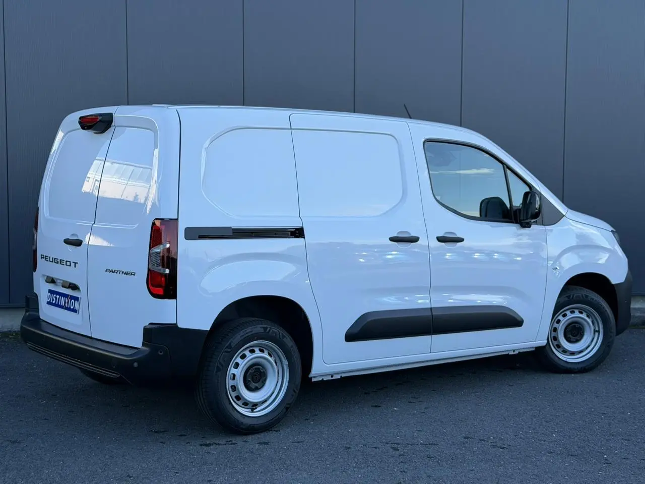 Vue 3/4 arrière droite du Peugeot Partner blanc Icy avec portes arrière battantes et protections latérales noires.