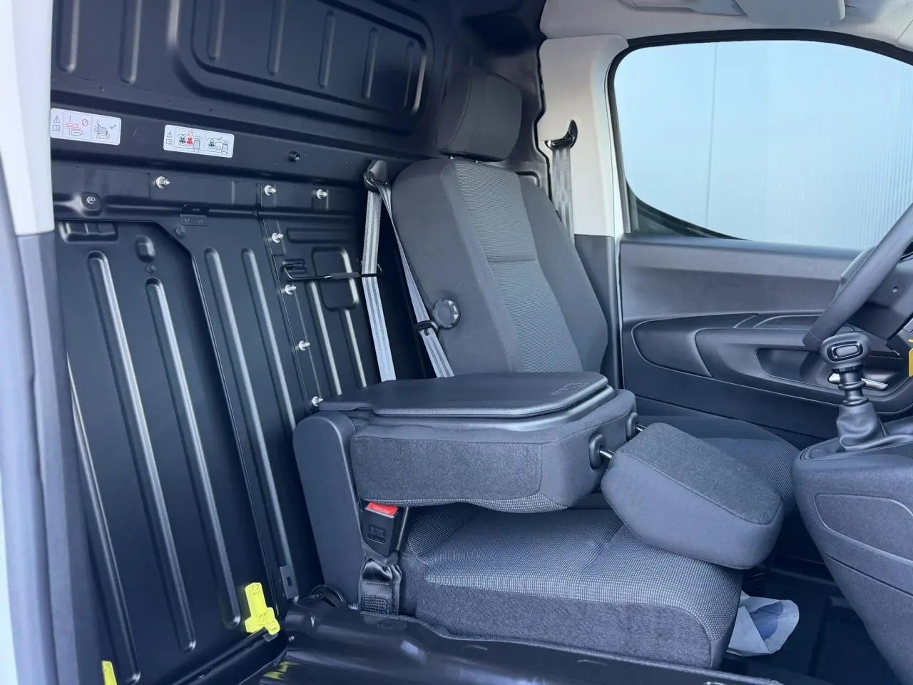 Vue intérieure côté droit du siège passager rabattable avec tablette écritoire dans un Peugeot Partner blanc Icy.