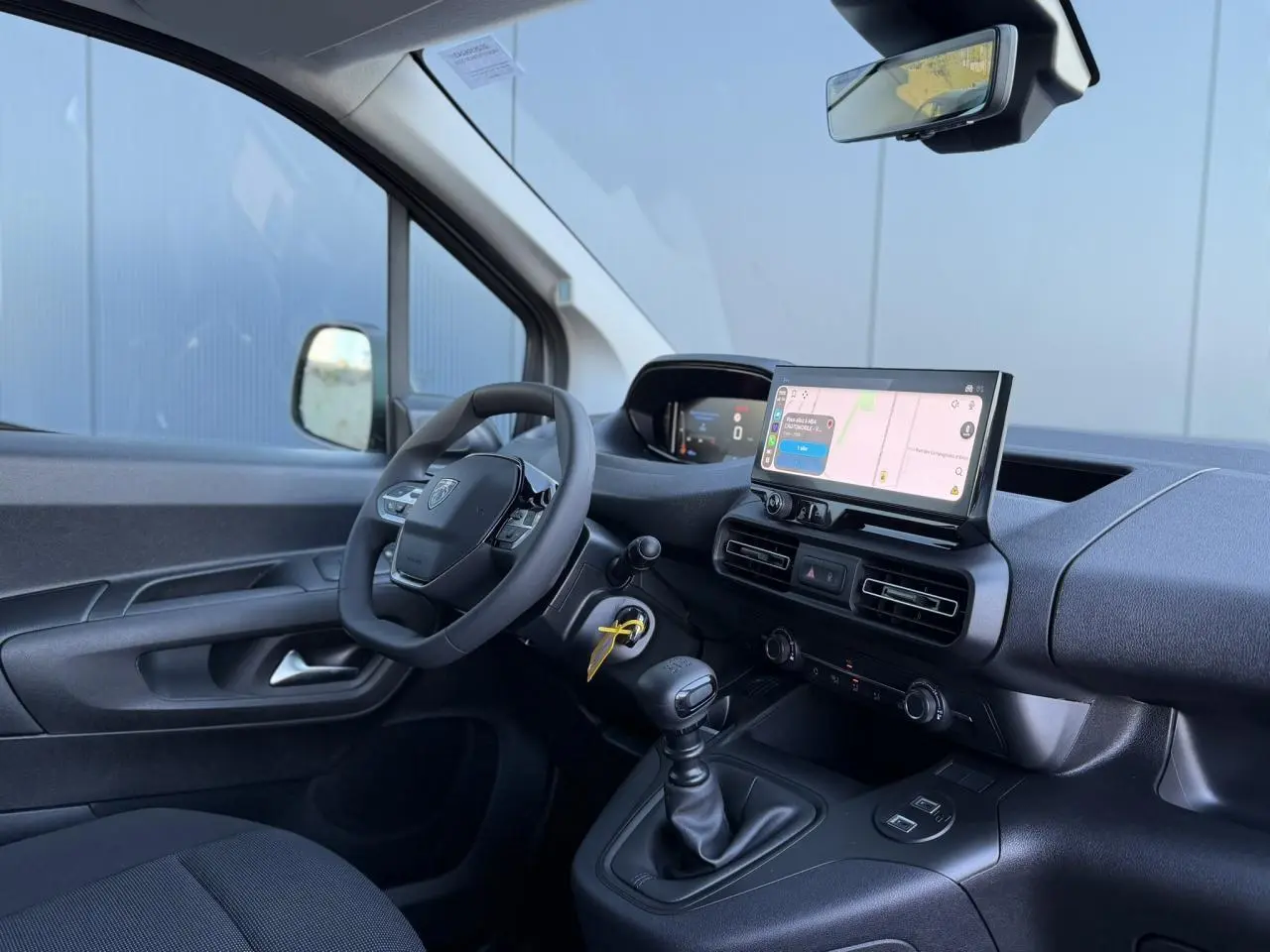 Vue intérieure côté conducteur du Peugeot Partner blanc Icy 2026, avec tableau de bord numérique et écran tactile central.