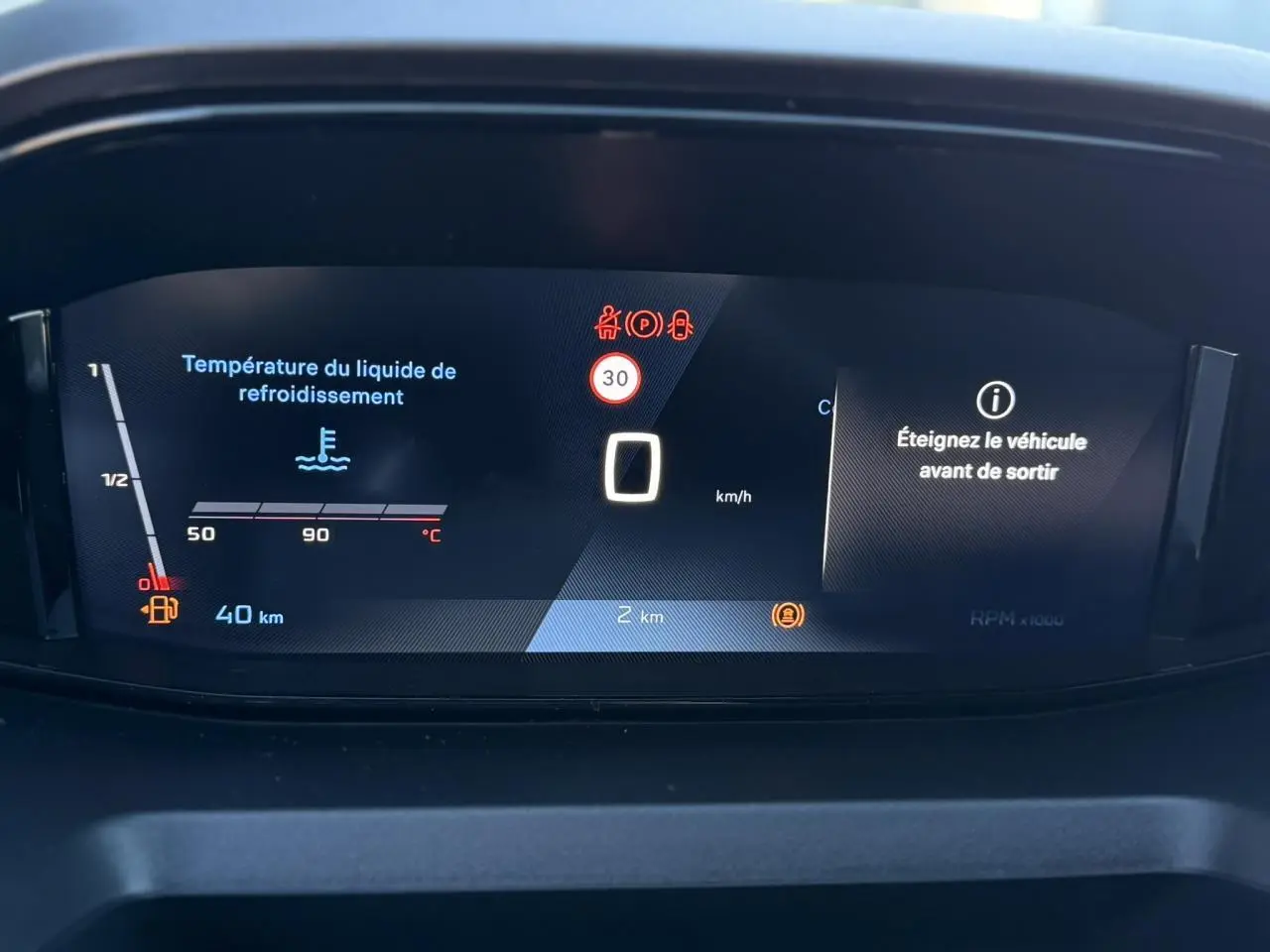 Affichage numérique du tableau de bord du Peugeot Partner 2026 montrant la température liquide de refroidissement et alertes véhicule.