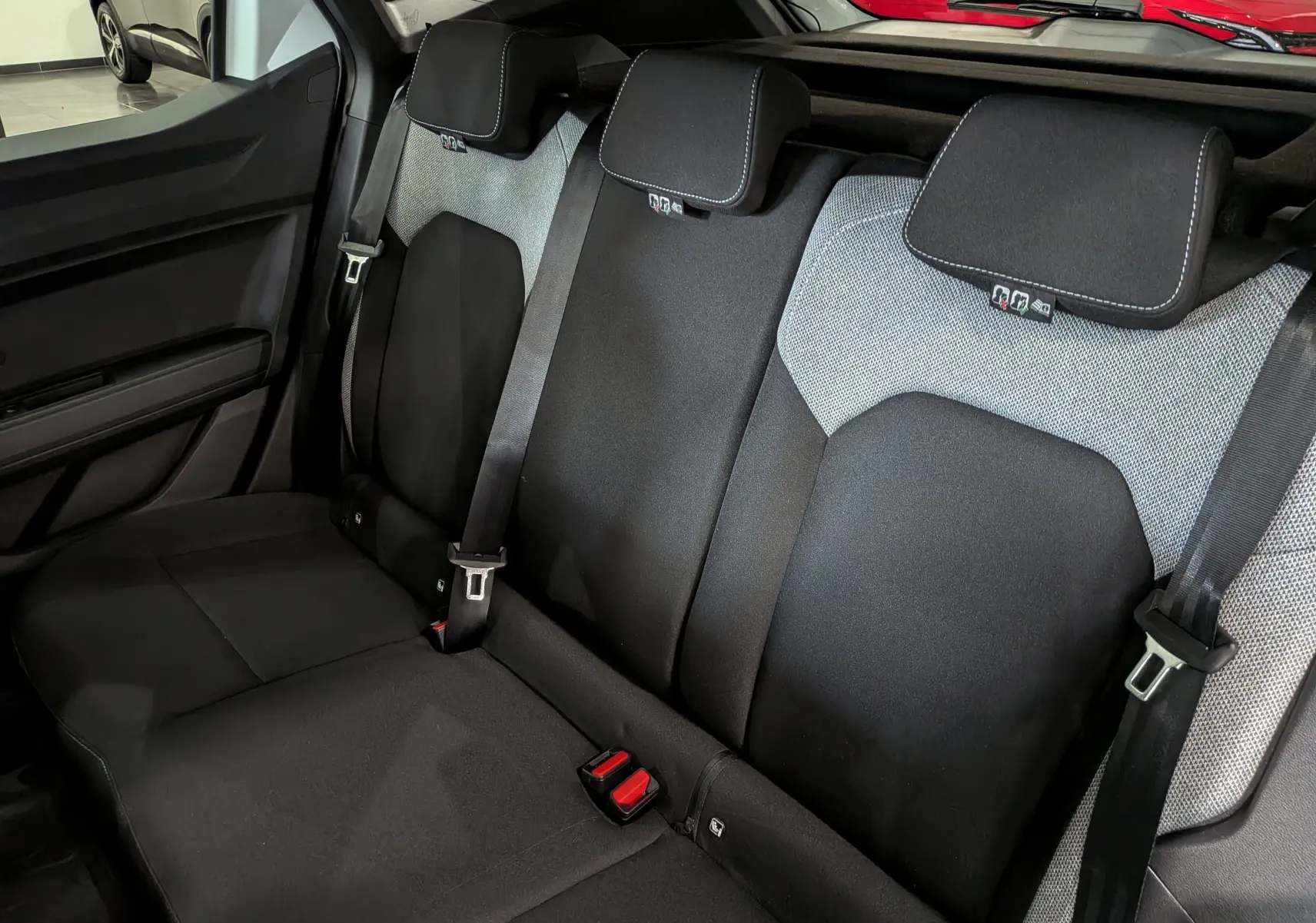 Vue intérieure du siège arrière du Dacia Duster Hybrid-G 150 CH 4x4, tissu noir et gris avec ceintures de sécurité visibles.