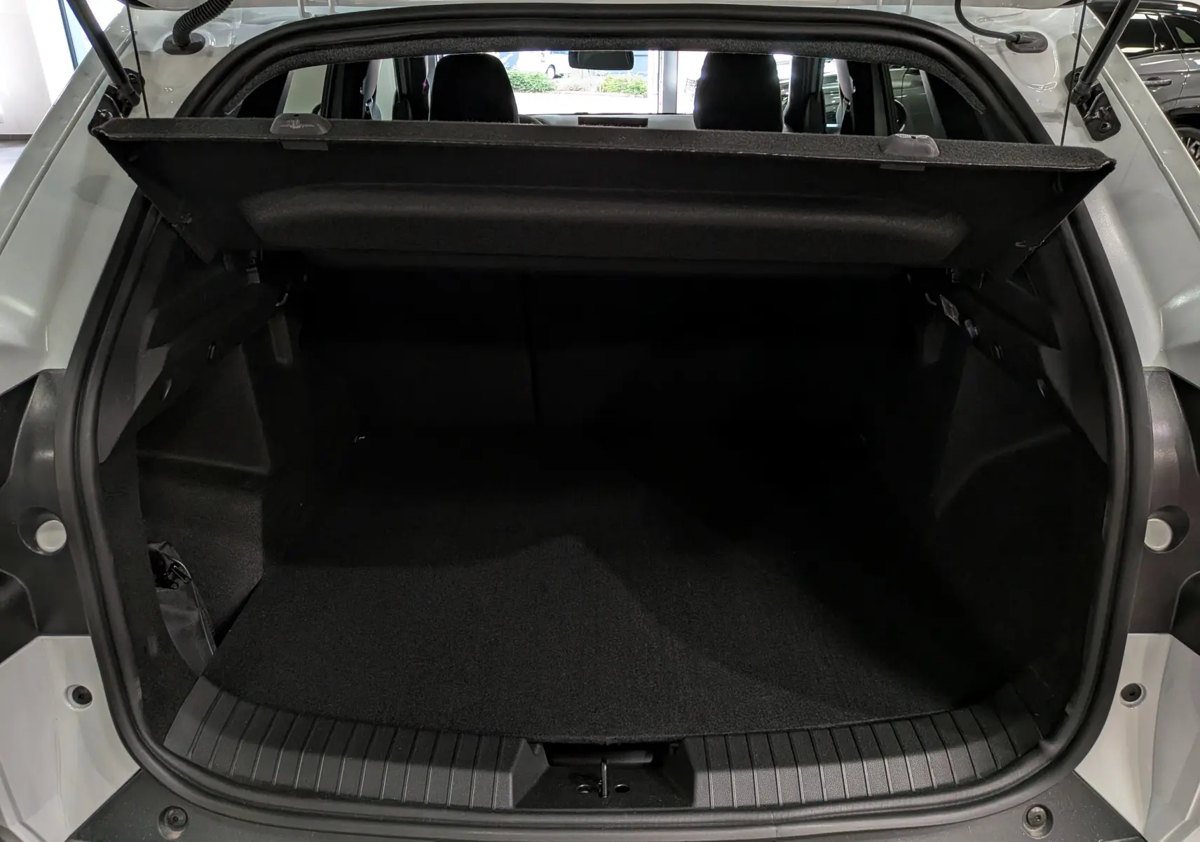 Coffre ouvert vu de l’arrière d’un Dacia Duster blanc Glacier, montrant l’espace de chargement et la plage arrière.
