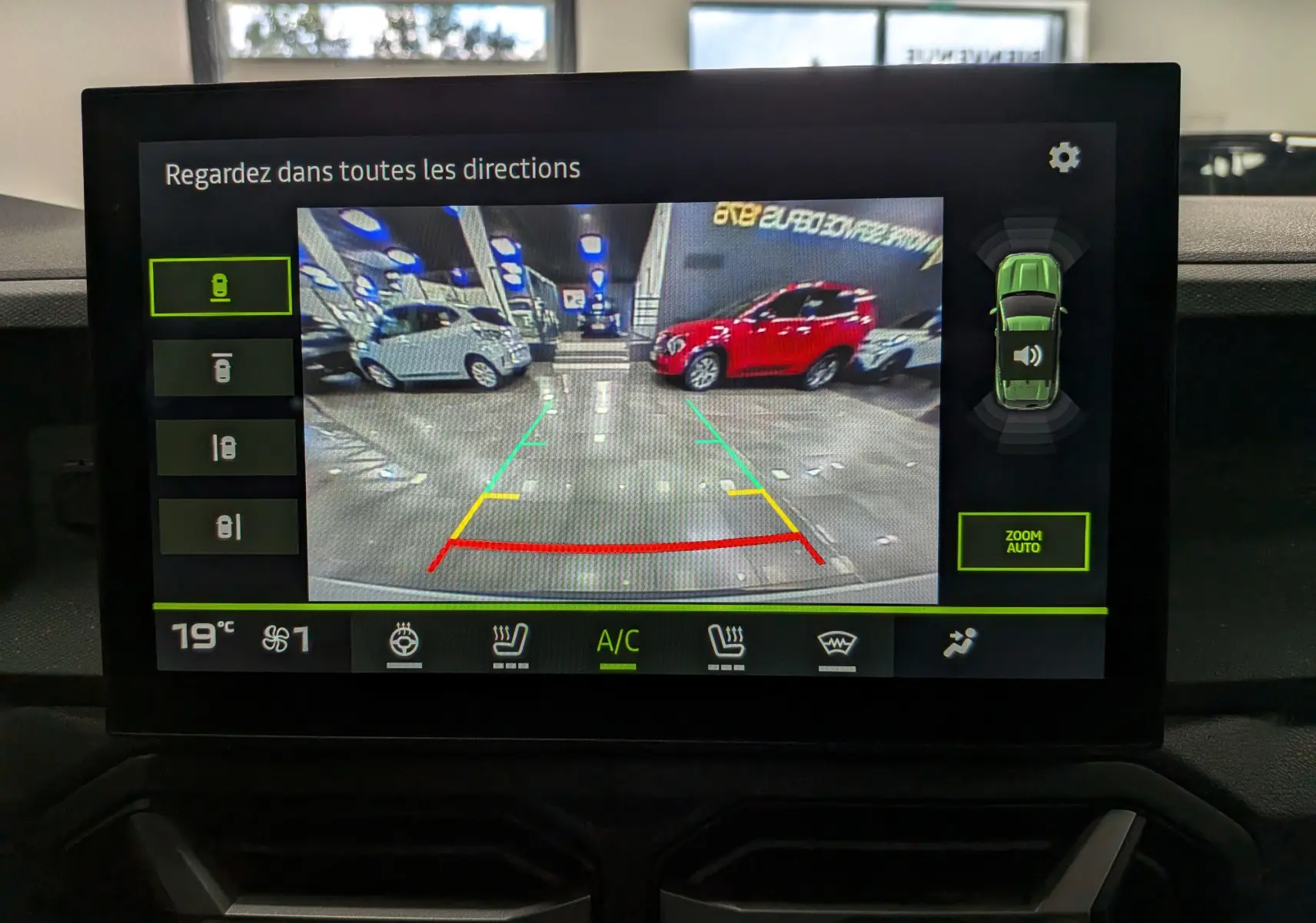 Vue caméra 360 du Dacia Duster blanc Glacier en stationnement intérieur, avec lignes d’aide au recul colorées.