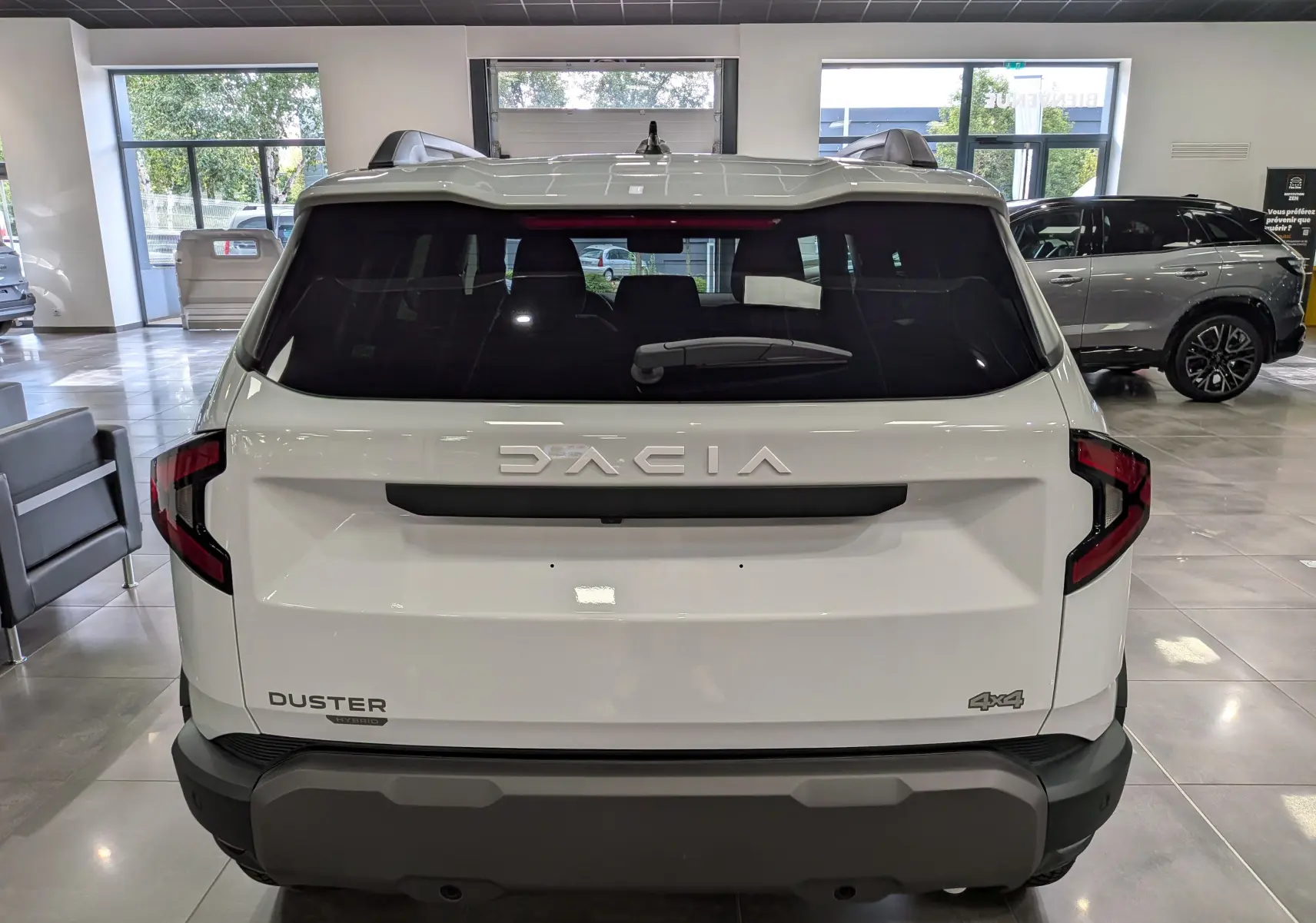 Vue arrière du Dacia Duster blanc Glacier 2026 avec logo DACIA et badge 4x4 visible en showroom.