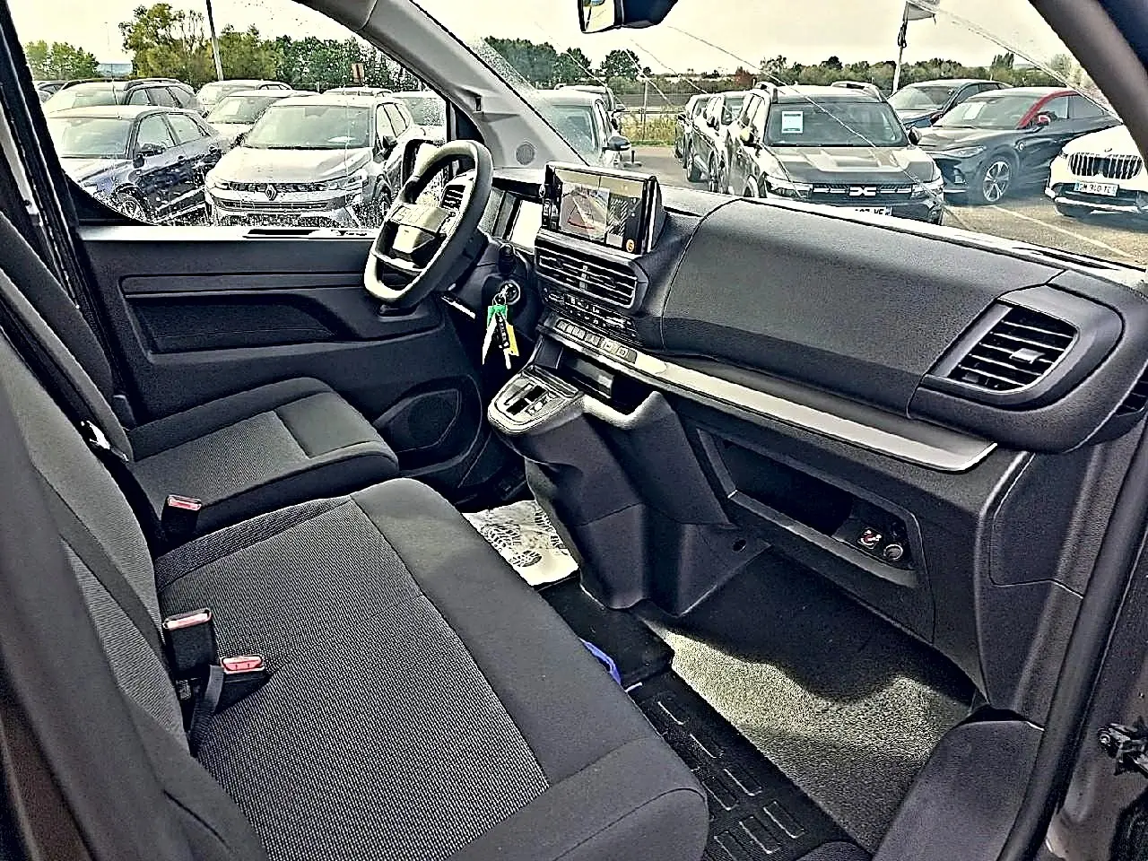 Vue intérieure côté conducteur du Fiat Scudo Combi 2026, sièges bi-ton noir/gris et tableau de bord moderne avec écran tactile.