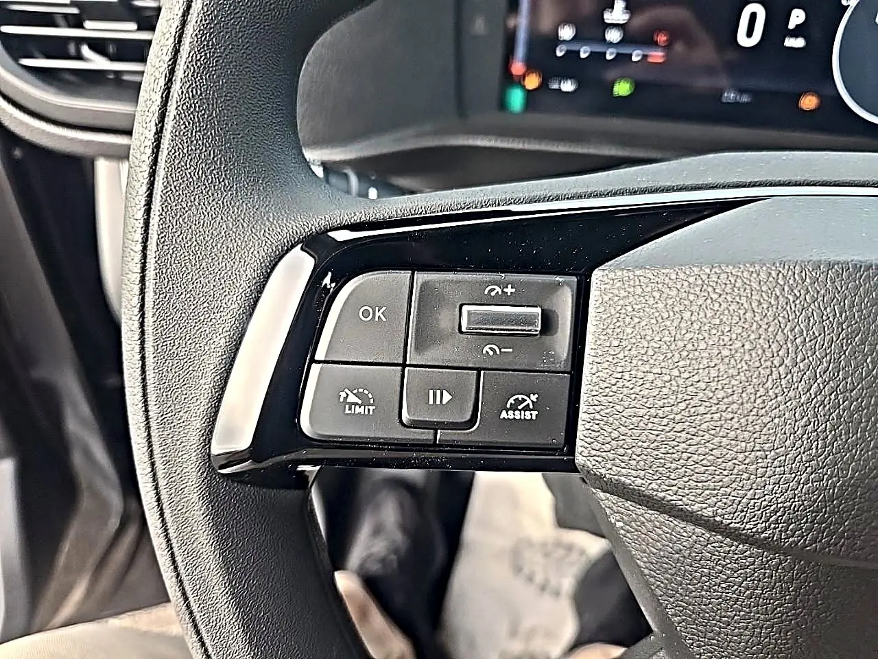 Gros plan sur les commandes à gauche du volant noir du Fiat Scudo Combi gris titane, avec affichage numérique en arrière-plan.