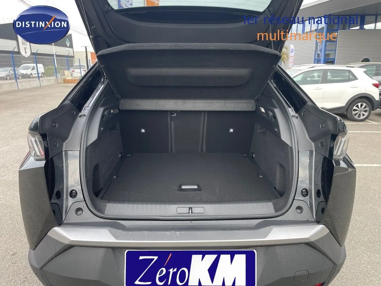 Coffre ouvert d'un Peugeot 3008 Hybrid noir métal vu de l'arrière, montrant un espace de chargement spacieux et propre.