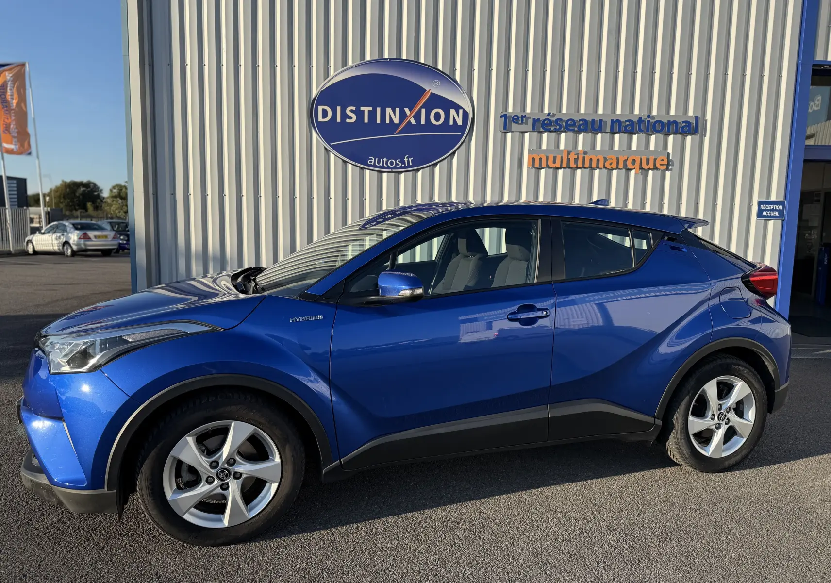 Profil côté gauche d'un Toyota C-HR bleu Nebula Hybrid 2018 avec jantes alliage et détails noirs contrastants.