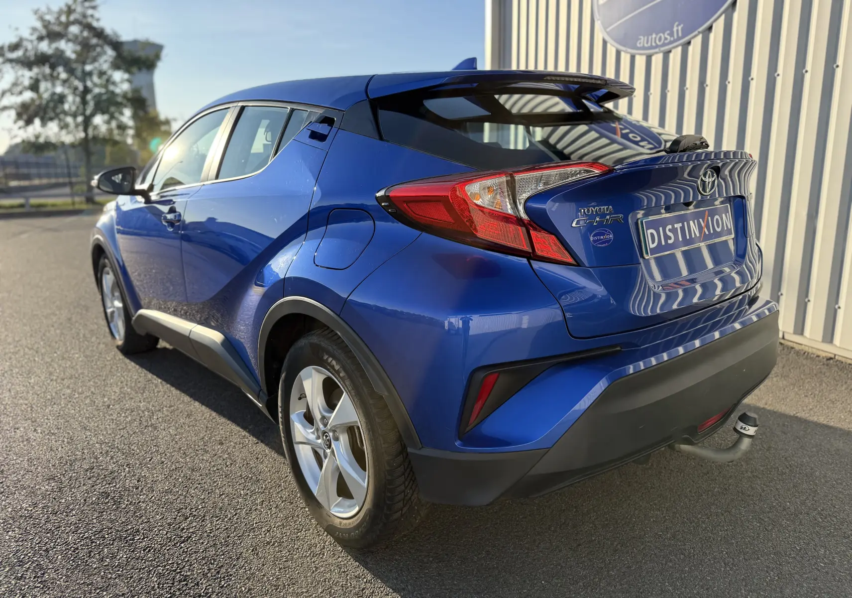 Vue 3/4 arrière droite du Toyota C-HR bleu Nebula Metal avec attelage et feux arrière distinctifs.