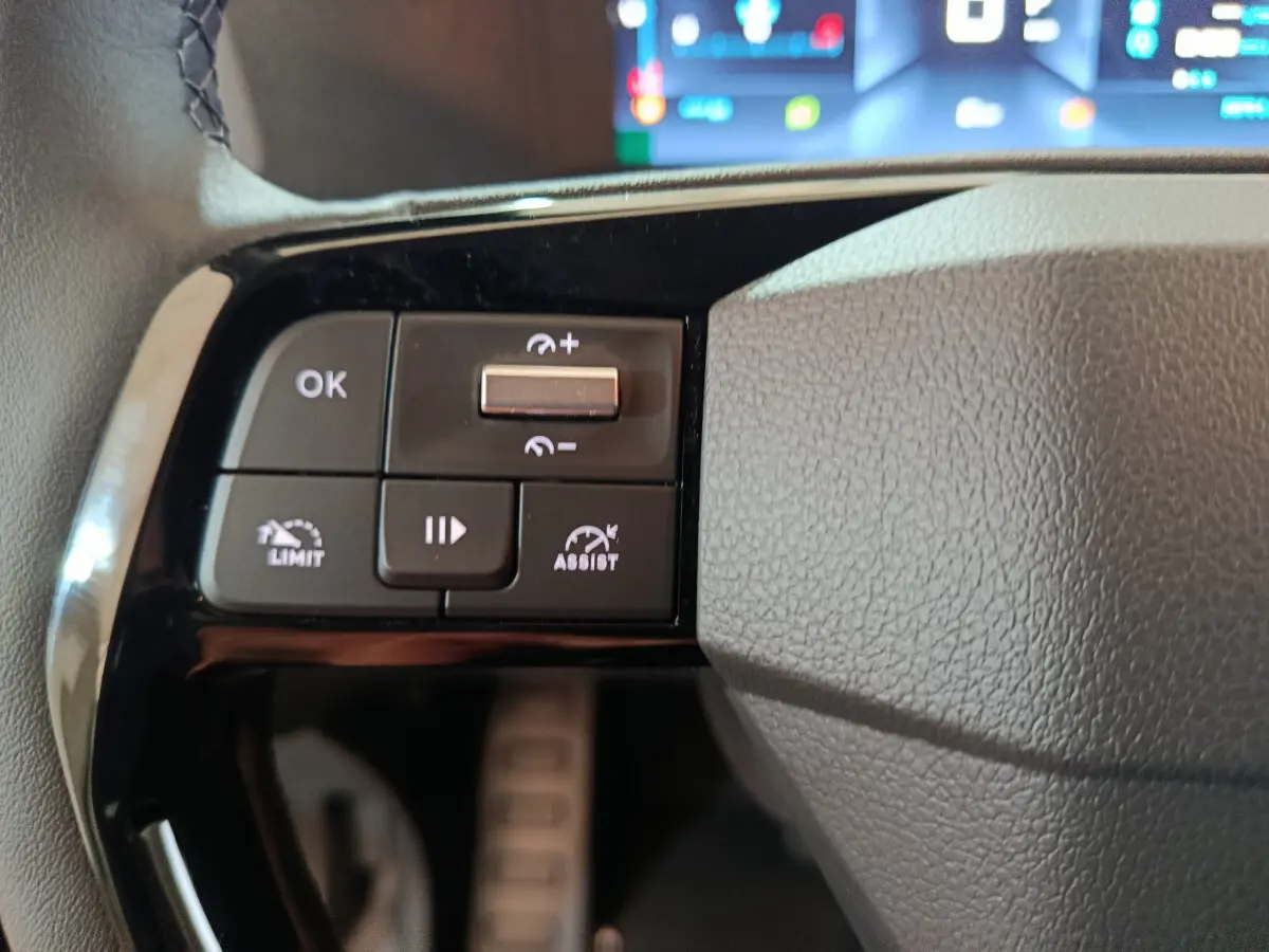 Gros plan sur les commandes noires du volant côté gauche du Citroën Jumpy XL 2025 avec affichage numérique flou en arrière-plan.