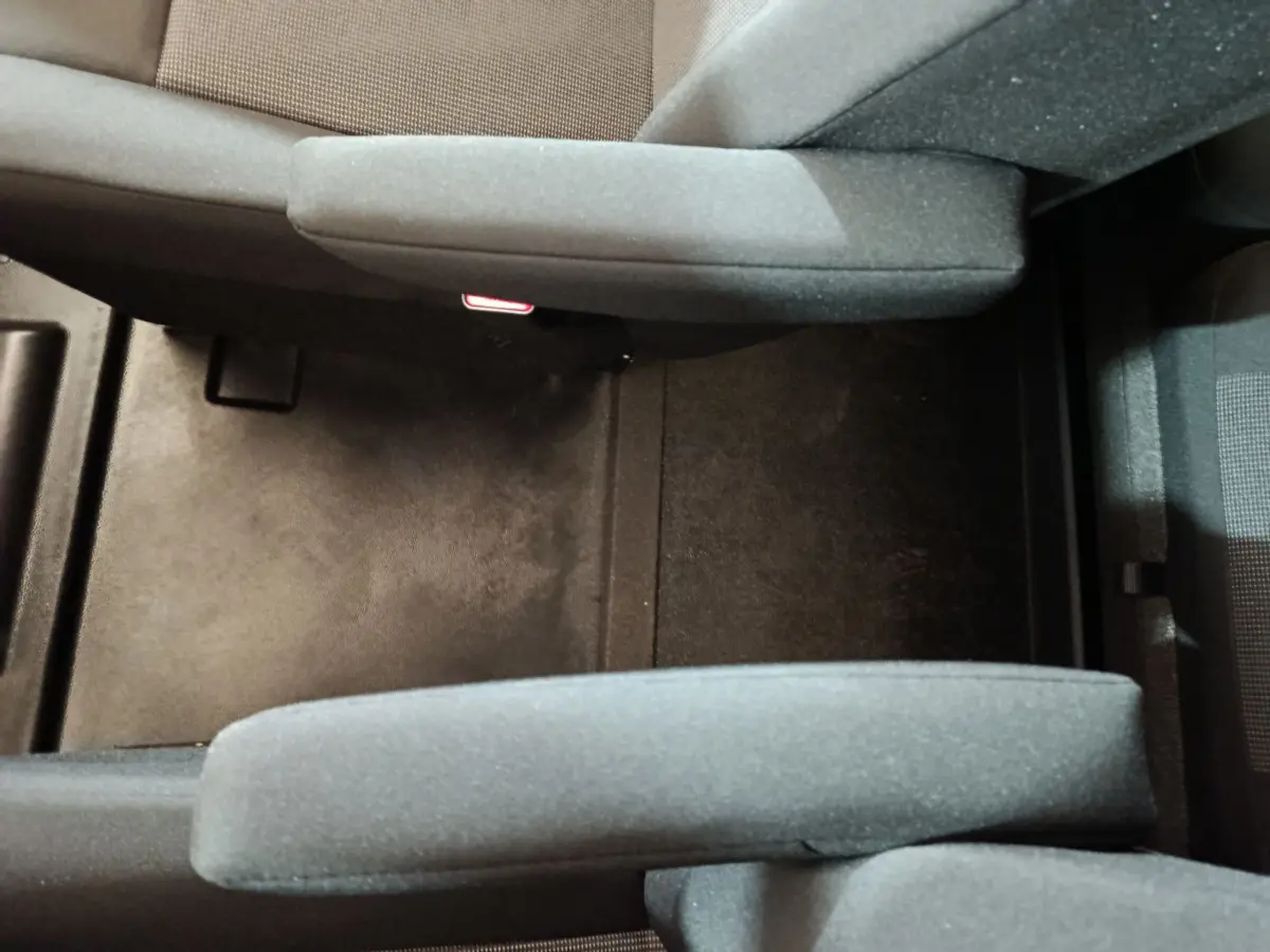 Vue plongeante sur l'espace entre les sièges avant gris foncé du Citroën Jumpy XL 2025, tissu et moquette noire.