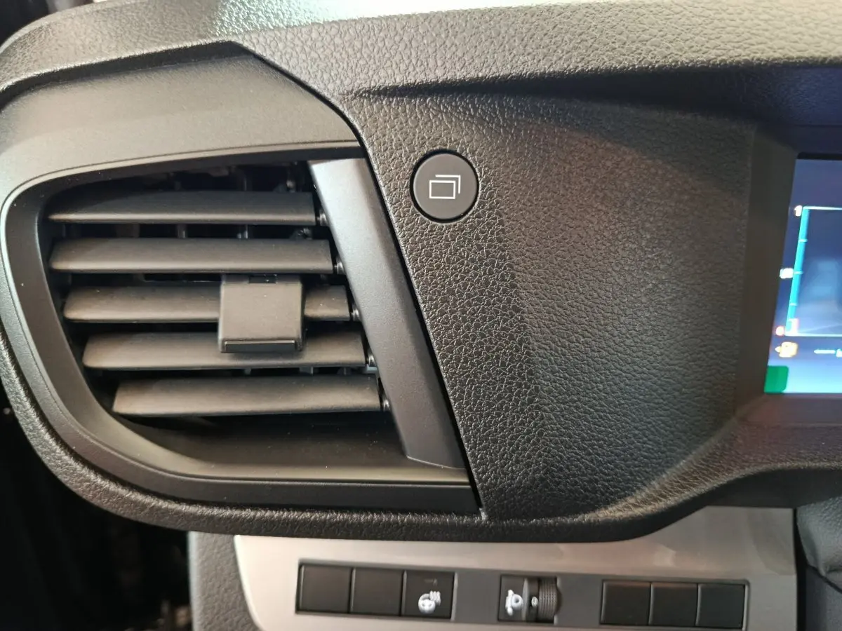 Détail intérieur du tableau de bord noir du Citroën Jumpy 2025, avec sortie d’air et bouton de commande carré.