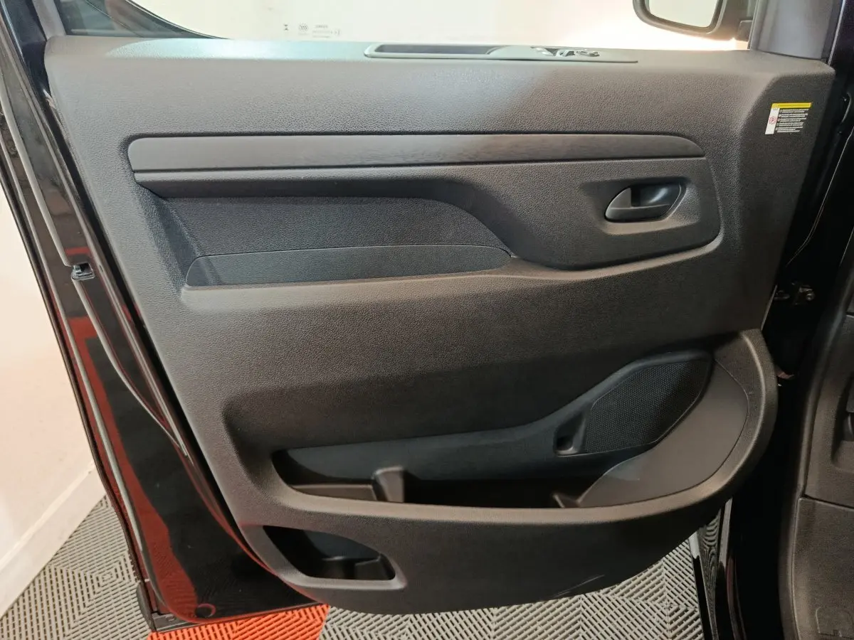 Gros plan sur la porte intérieure côté gauche du Citroën Jumpy XL noir, montrant la poignée et les rangements intégrés.