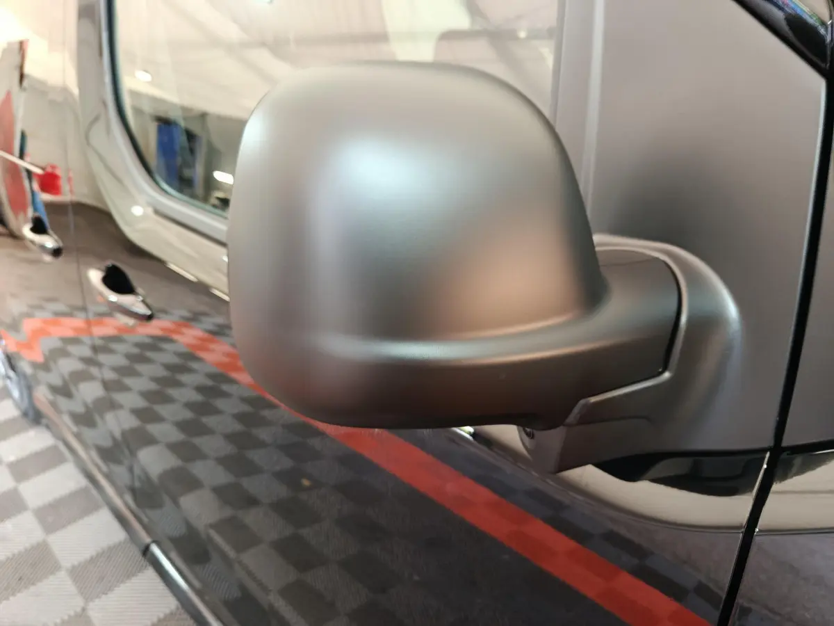 Gros plan sur le rétroviseur côté conducteur du Citroën Jumpy XL noir, reflétant partiellement la porte latérale du véhicule.