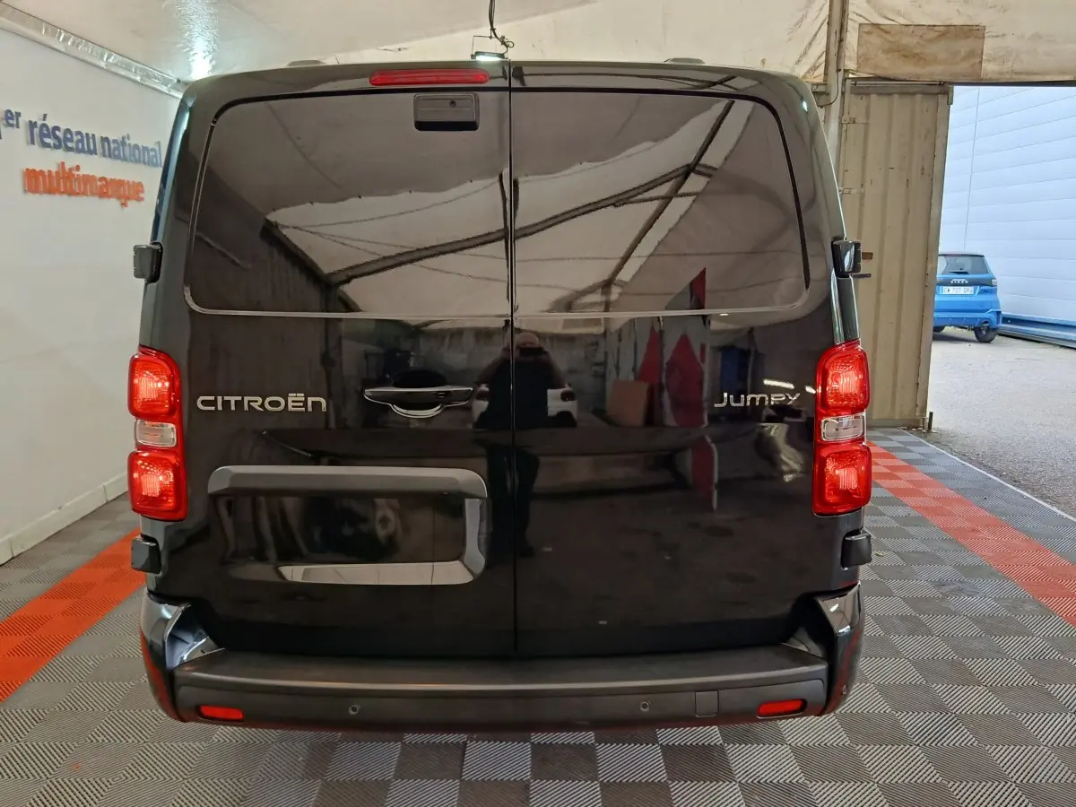 Vue arrière du Citroën Jumpy XL noir 2025, portes battantes fermées et feux arrière allumés en intérieur.