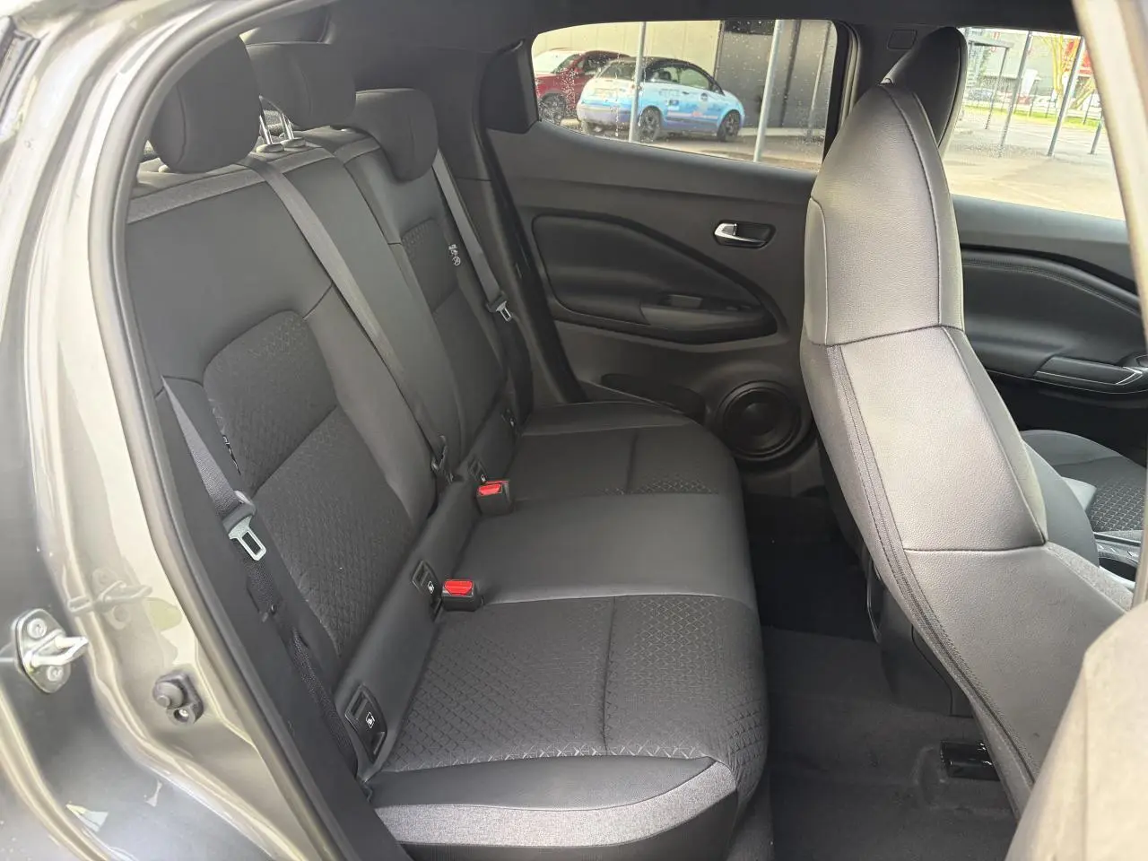 Vue intérieure côté gauche montrant la banquette arrière noire et les sièges avant du Nissan Juke II 1.6 Hybrid N-Connecta.
